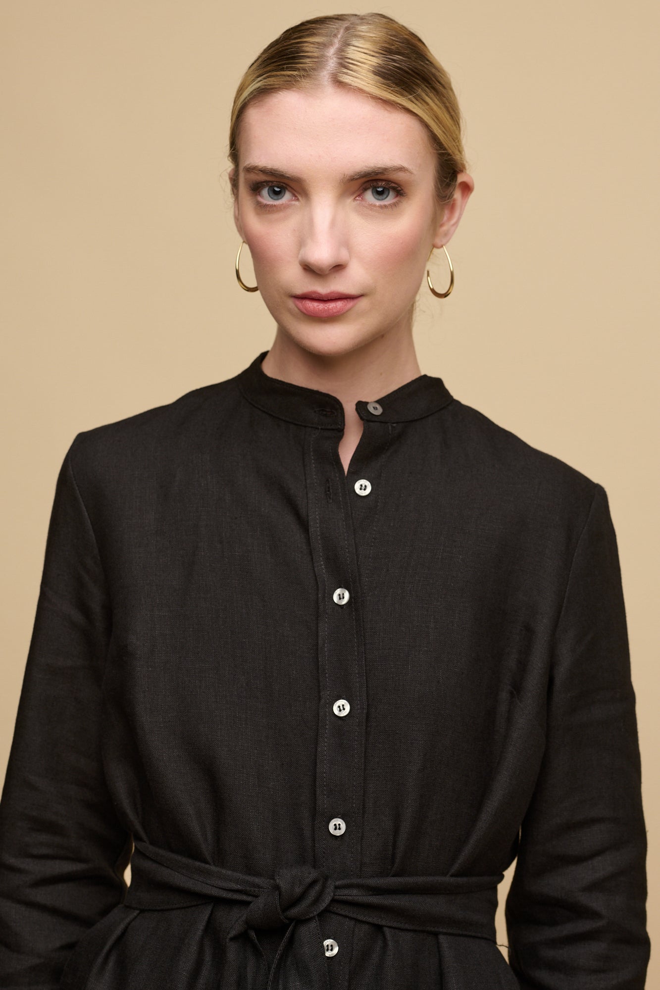 Waist up image of female wearing collarless shirt dress in black linen