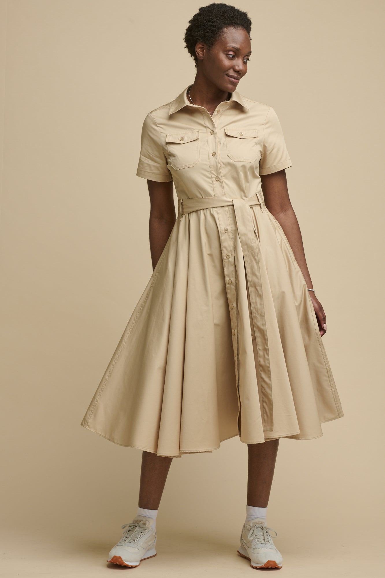 Image of the front of female wearing full skirted phoebe trench dress in stone