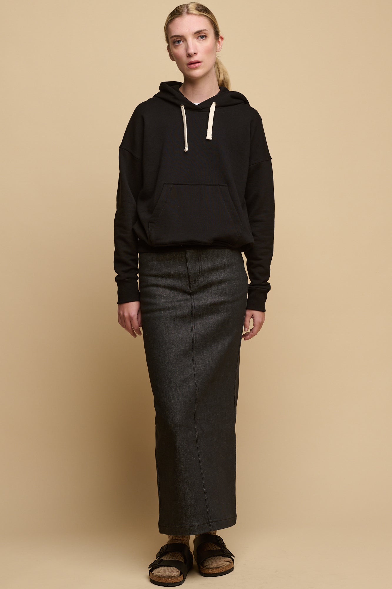 Female wearing hooded sweatshirt in black paired with denim maxi skirt in black