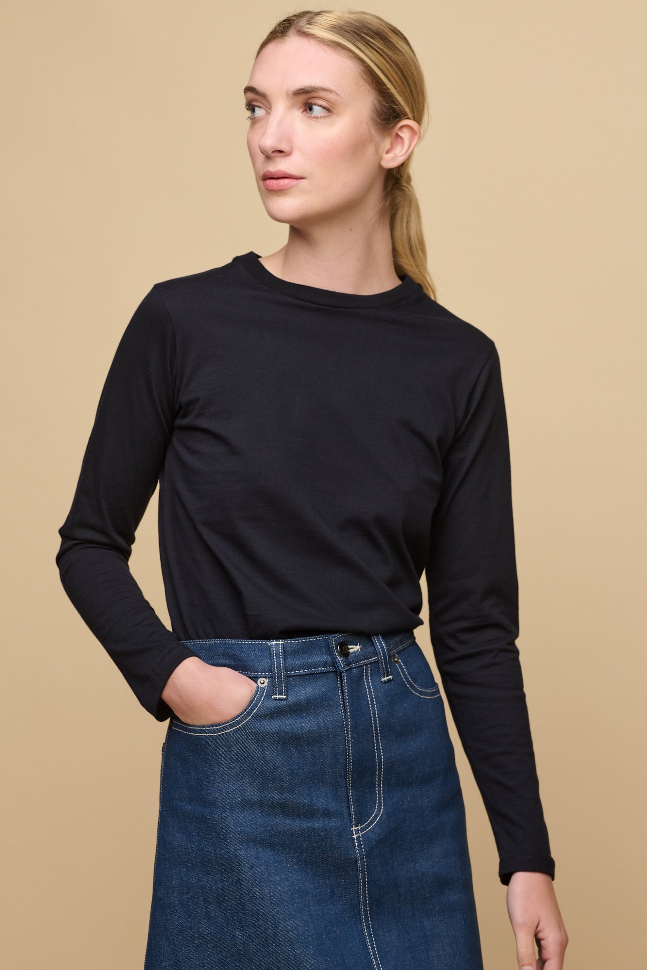 Female wearing long sleeve t-shirt in navy tucked into blue denim midi skirt