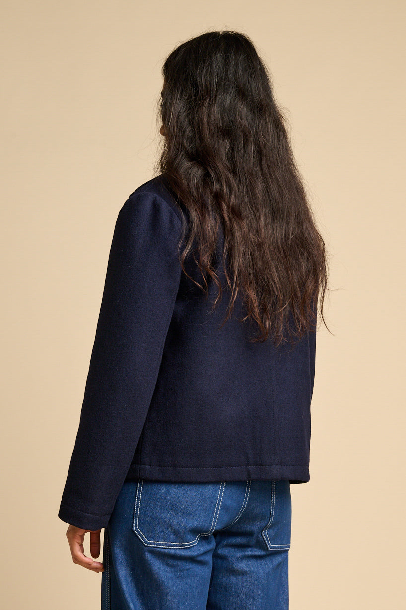 The back of a woman wearing Nancy short wool coat in navy paired with blue jeans.
