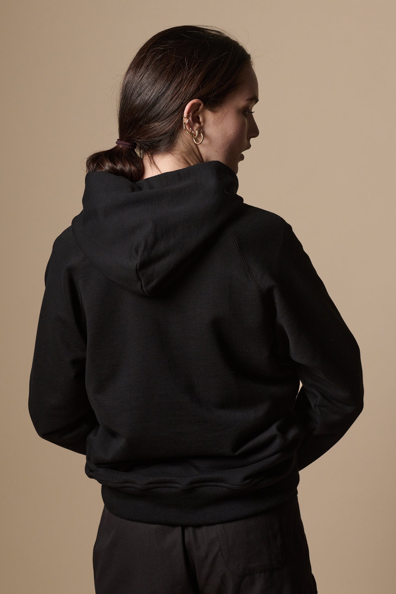 Back of female wearing women's raglan hooded sweatshirt plastic free in black