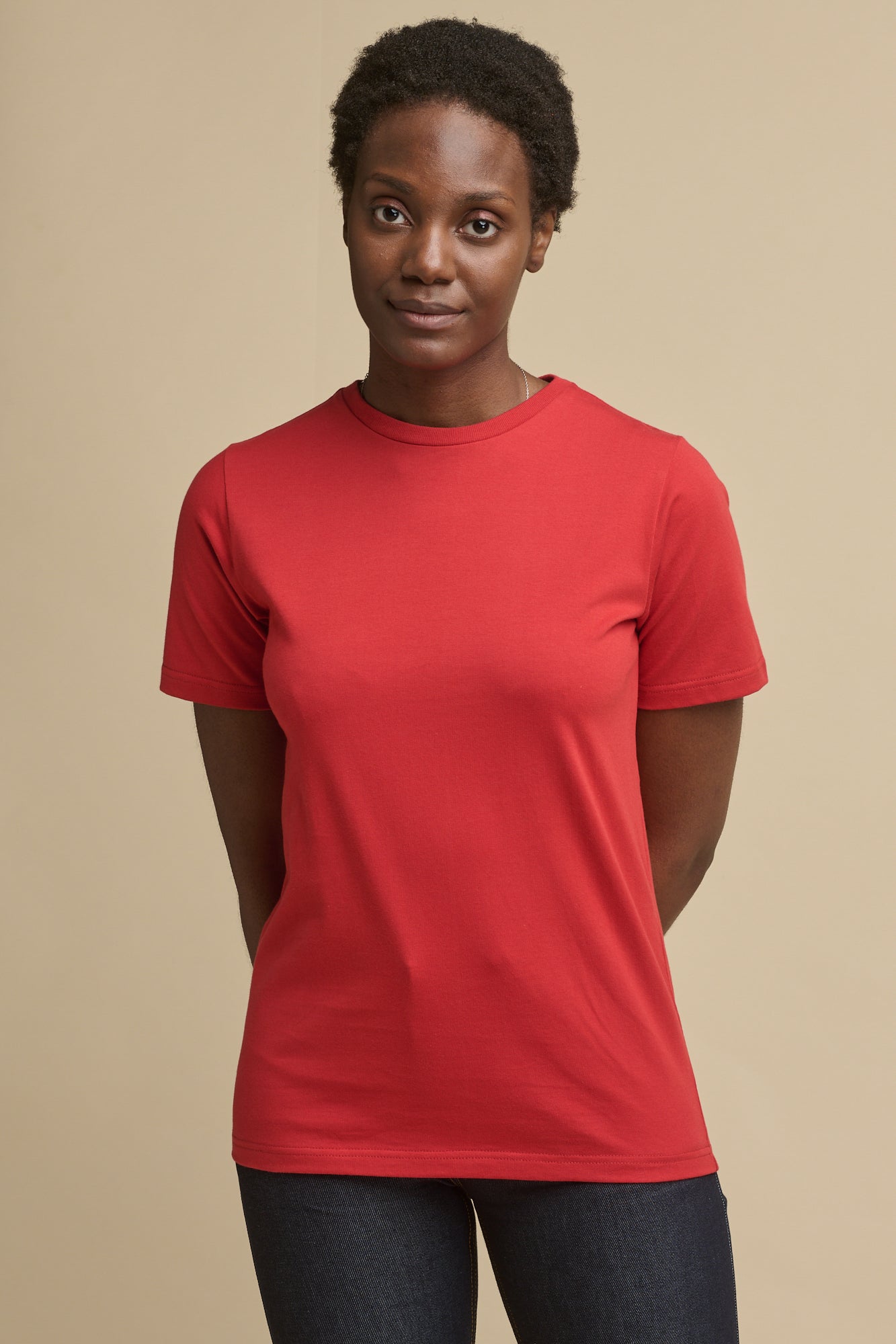 Thigh up image of the front of female wearing short sleeve t shirt in crimson