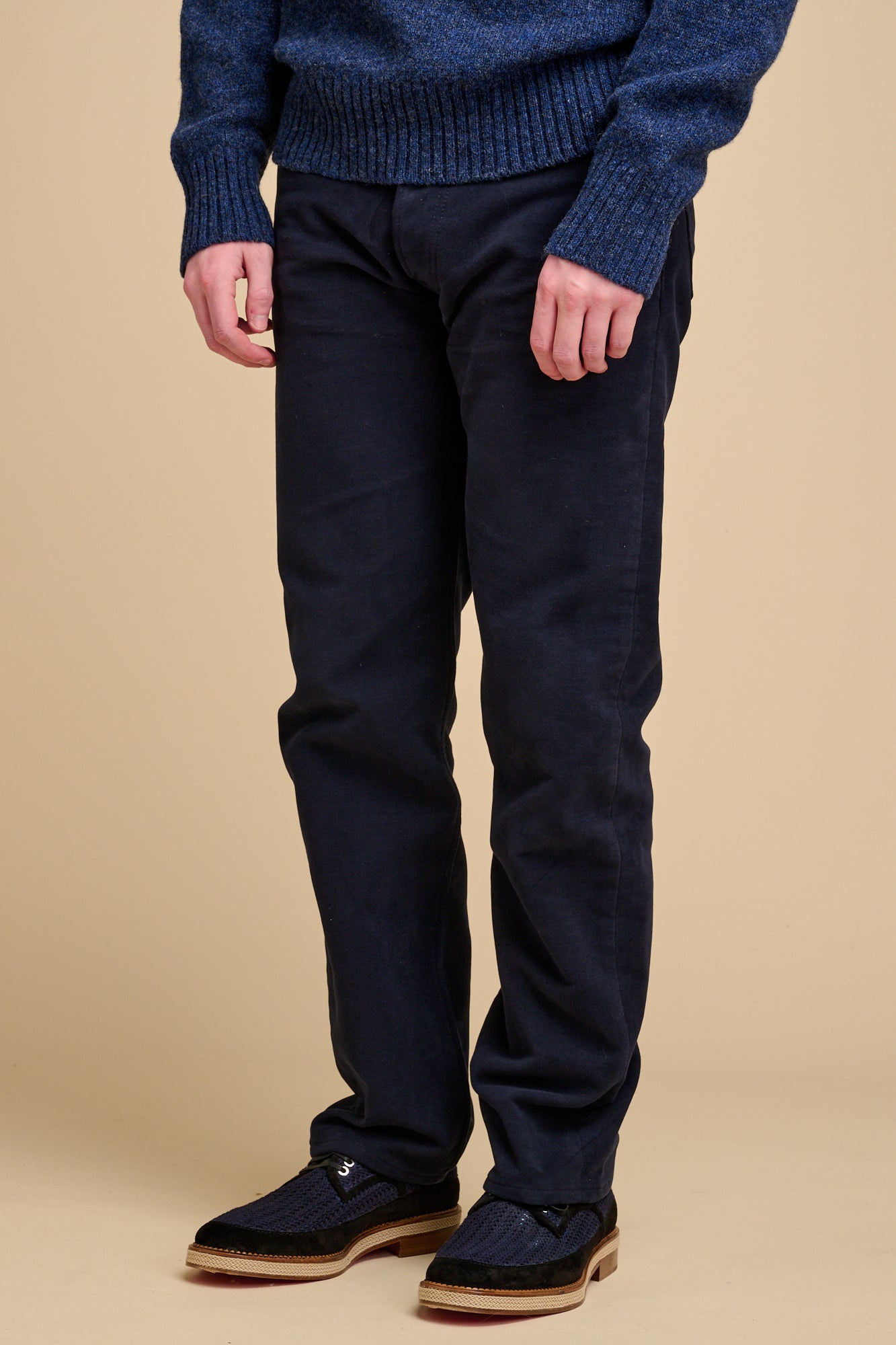 Male navy wearing moleskin jeans on beige background.
