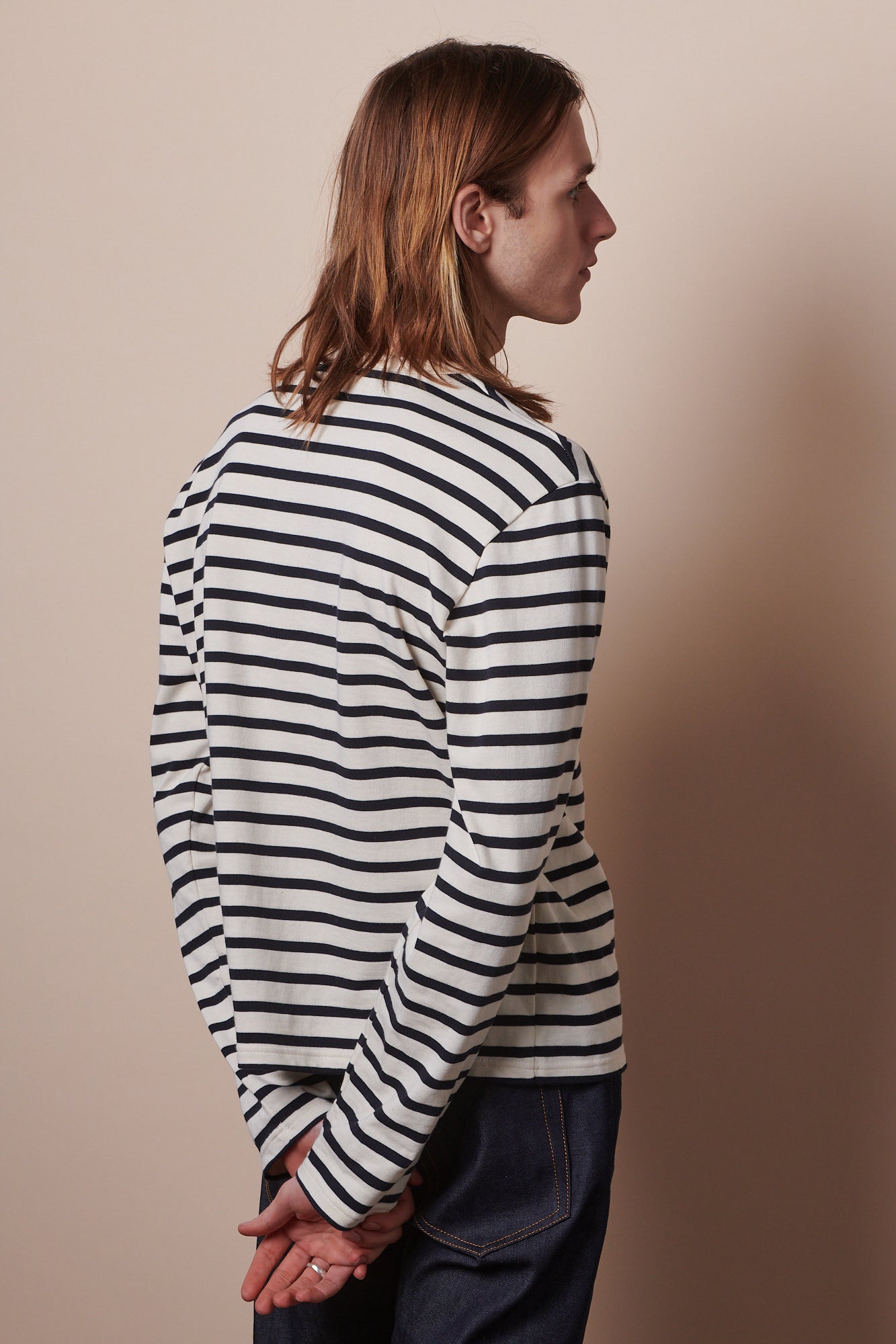 Thigh up image of the back of male wearing Breton in ecru navy