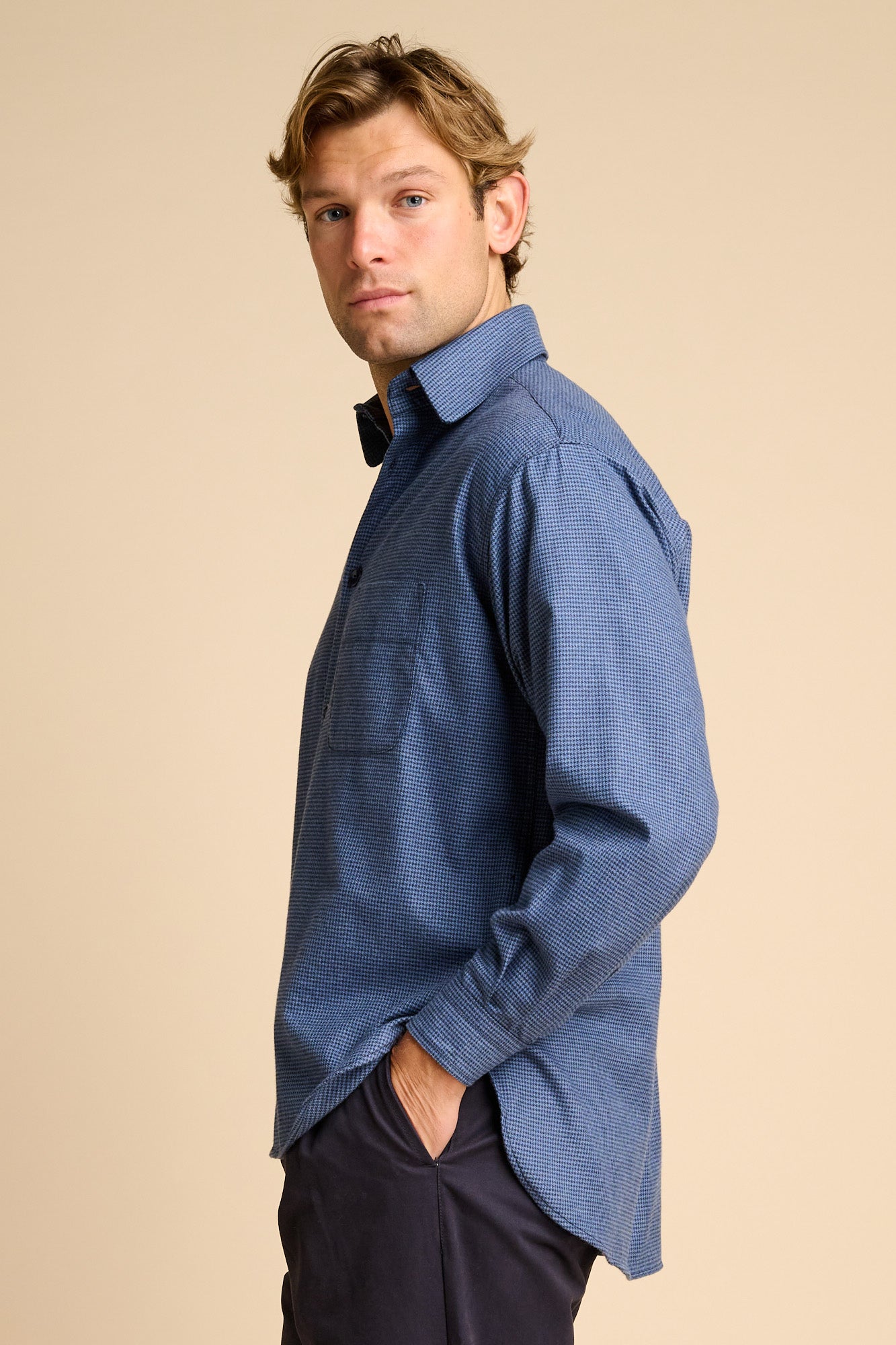 Man wearing blue shirt against beige background.