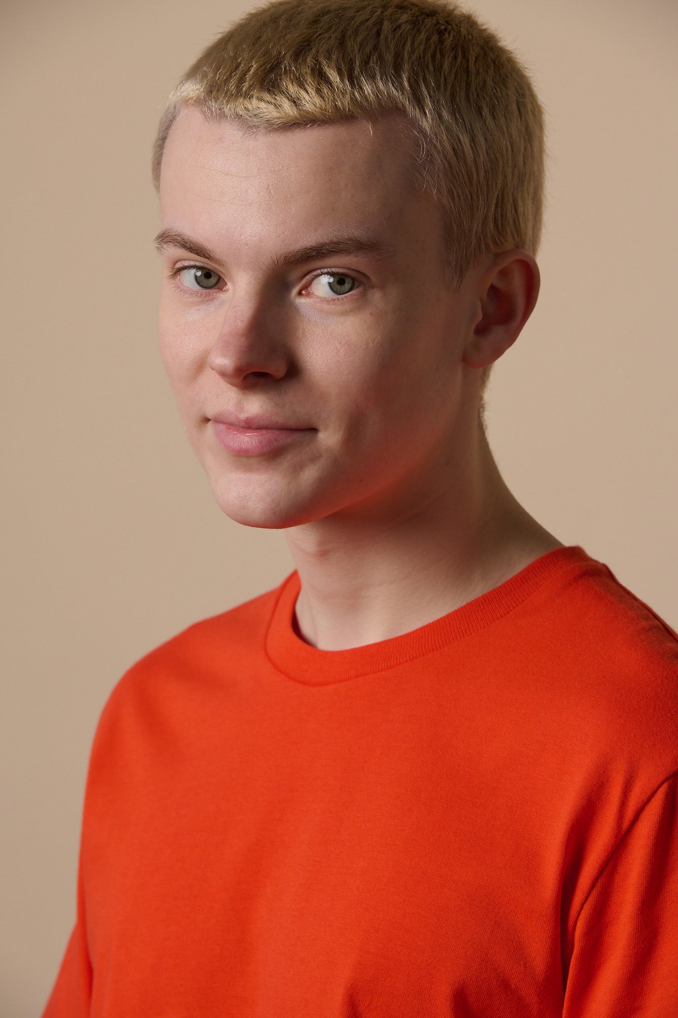 Portrait of white male with short blonde hair wearing short sleeve t shirt in flame red