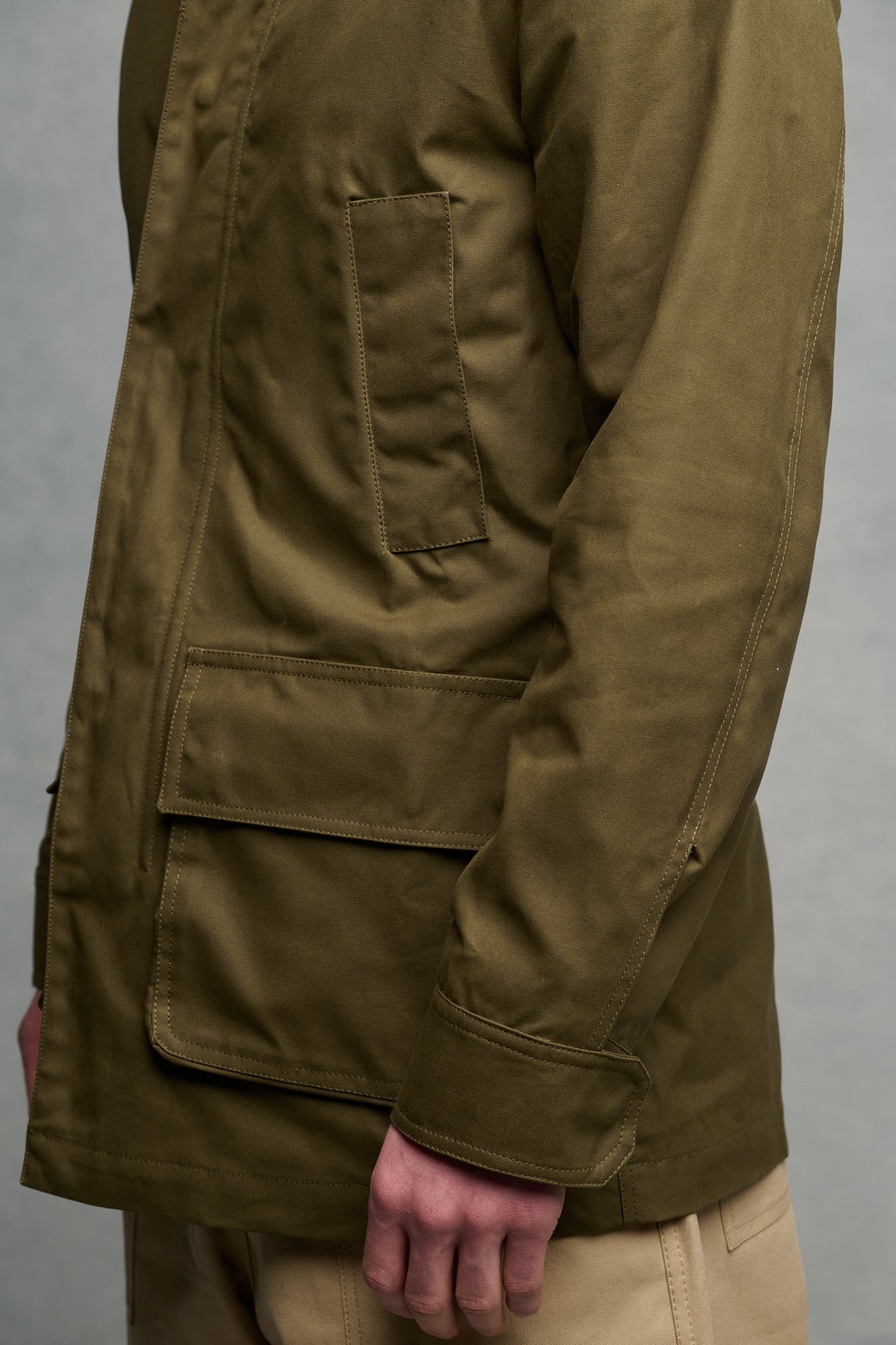 Close up of the side of males torso wearing barn jacket in olive, showing front pockets