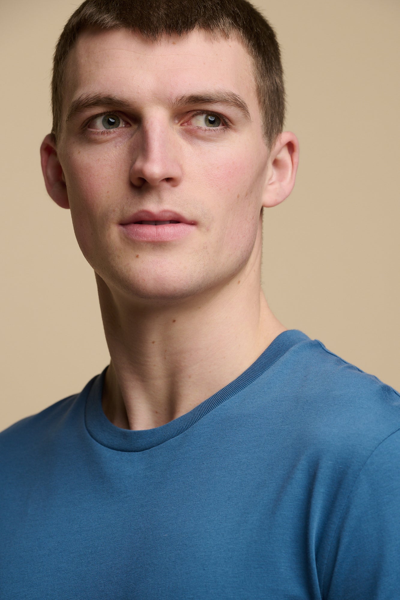 Portrait of brunet male wearing crew neck, short sleeve t shirt in RAF blue