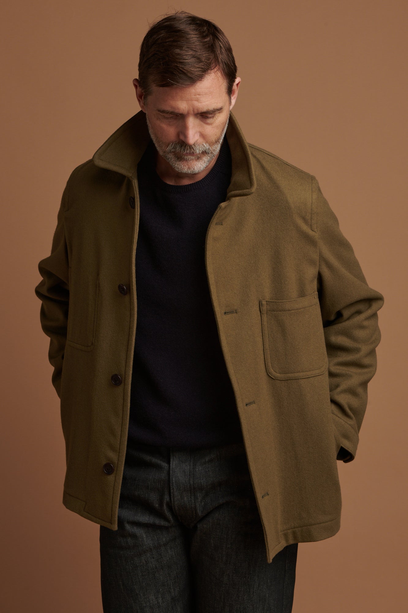 Patrick Grant wearing Community Clothing Arthur wool chore jacket in olive with the collar up. Worn over lambswool saddle shoulder crew neck in navy.