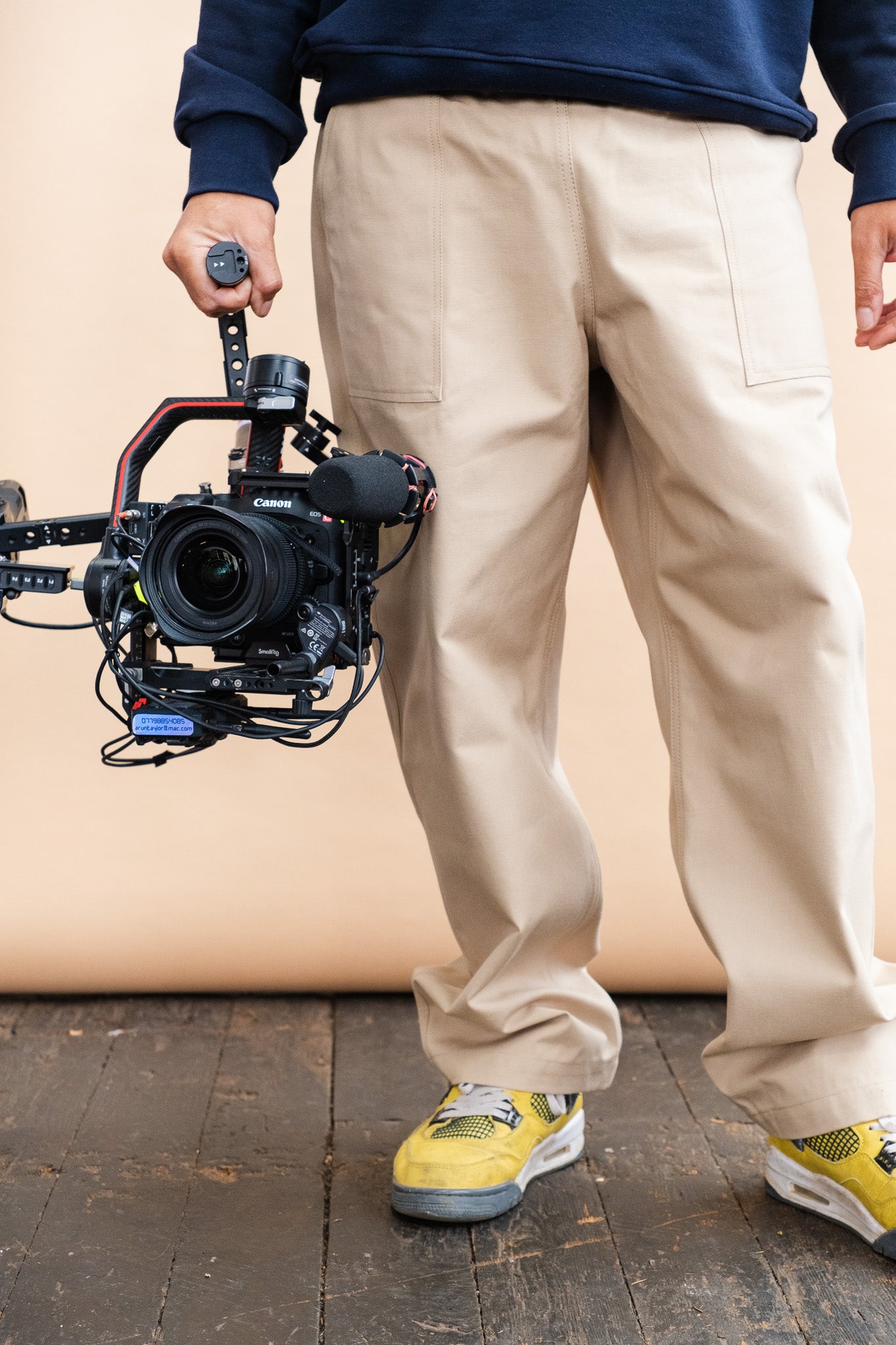 male wearing cameraman pant in putty, holding a camera 