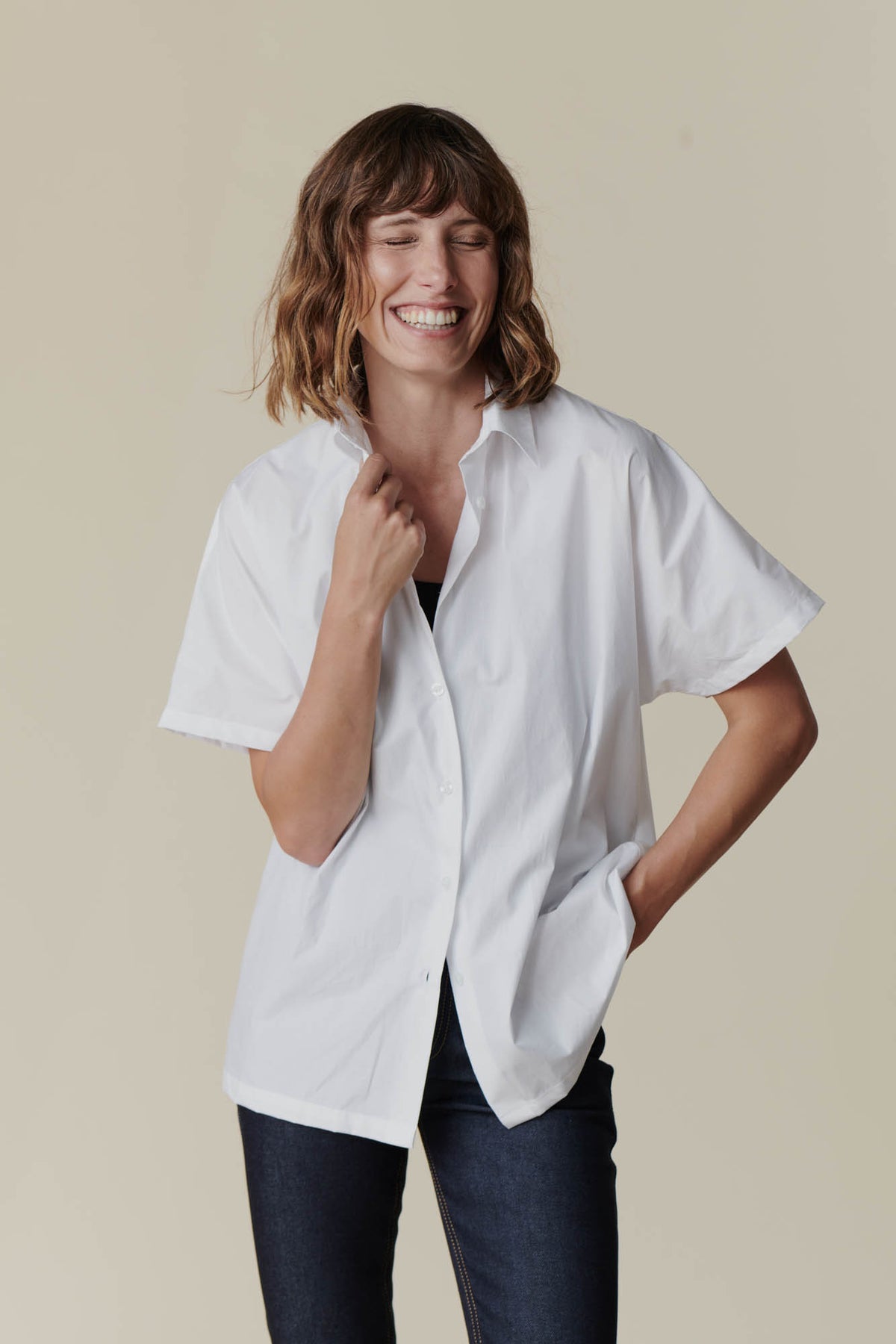 Female wearing Ava short sleeve shirt in white over black camisole