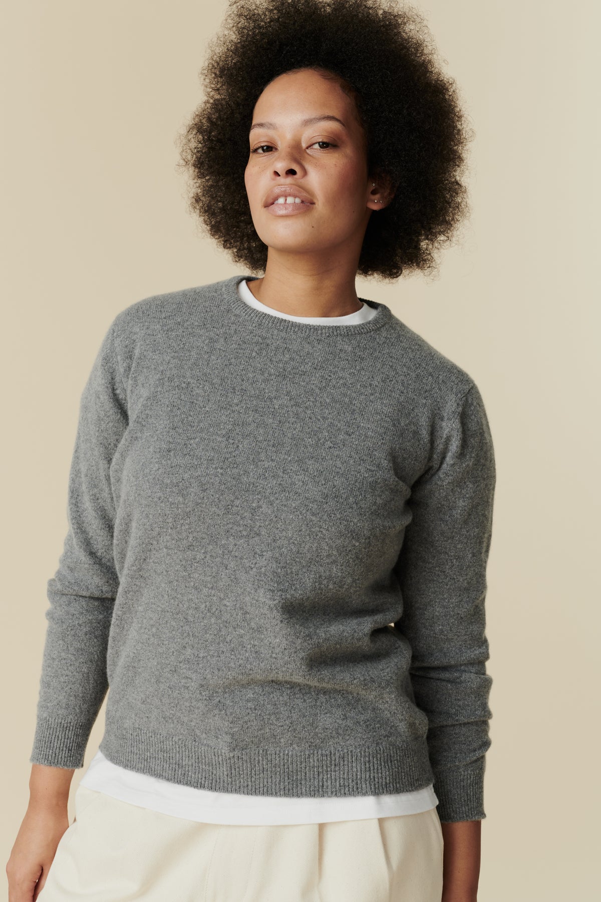 Woman wearing a gray sweater against a beige background
