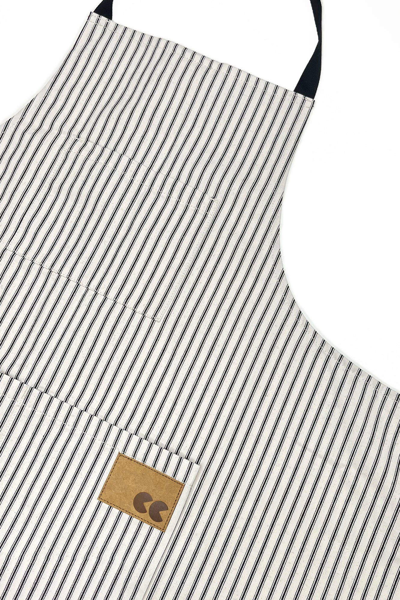 Black and white striped apron with a brown logo label on a white background.