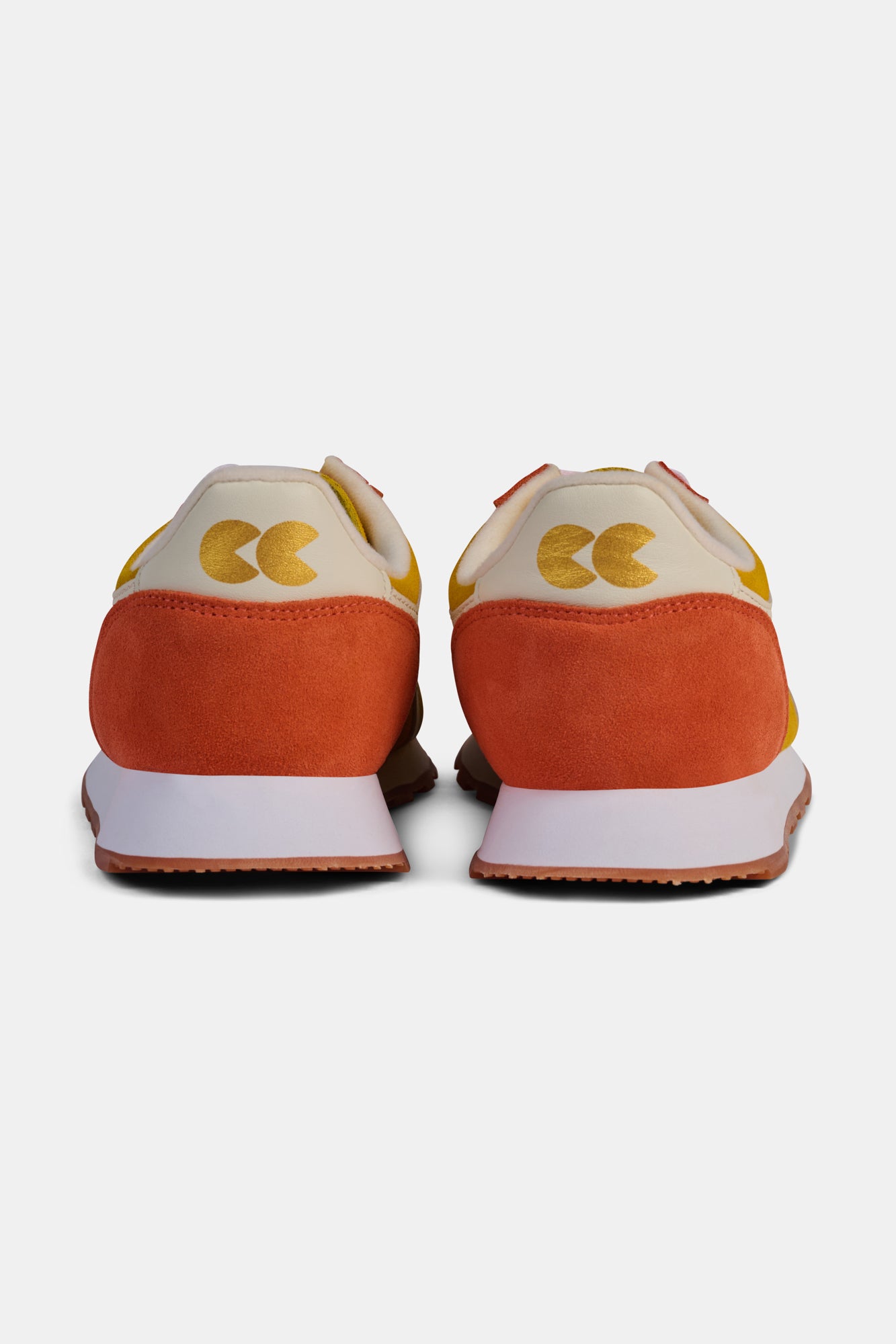 Pair of orange and yellow trainers on a white background.