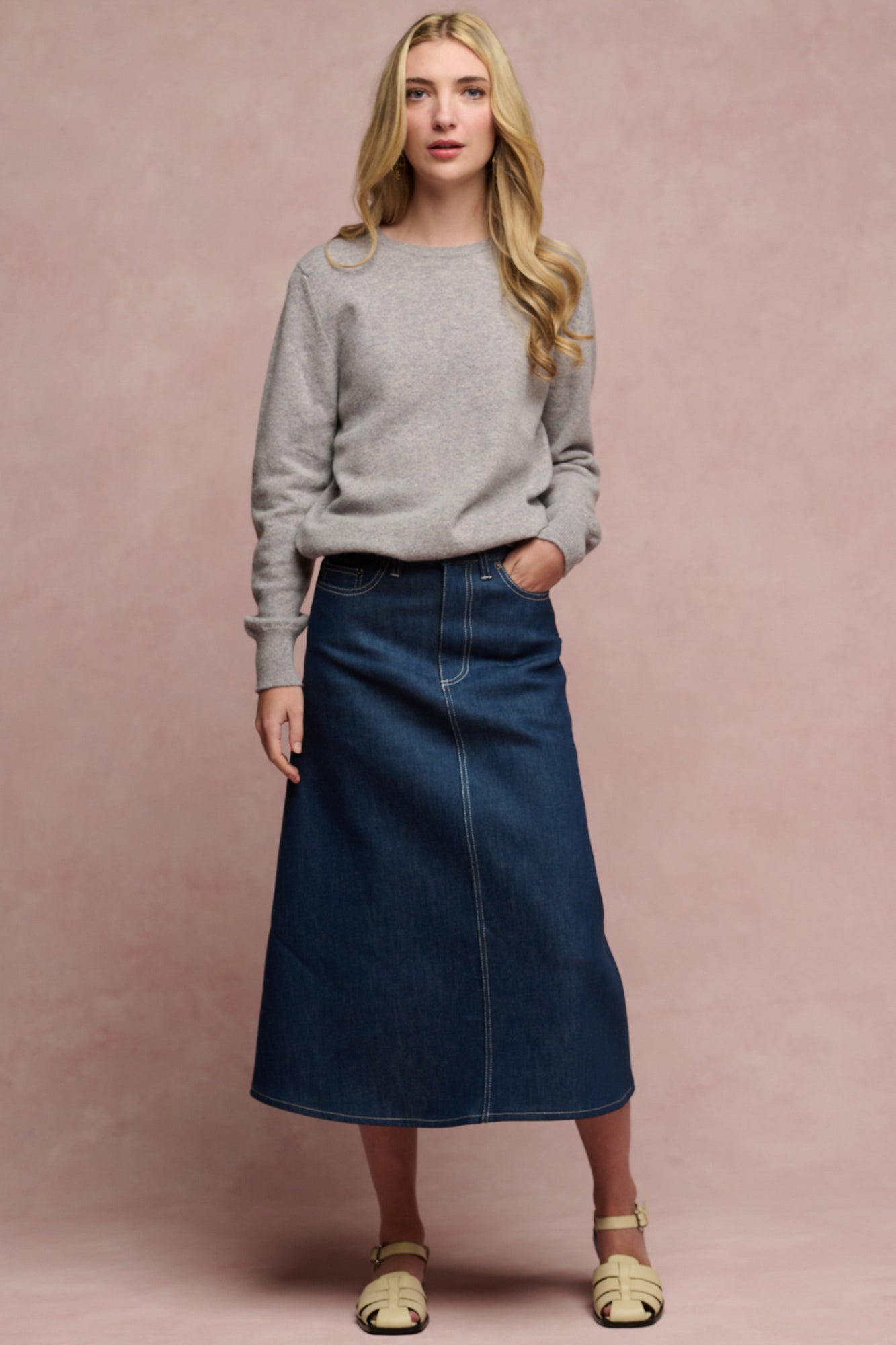 Full body image of blonde female wearing Bobbie a line midi skirt in blue paired with grey lambswool crew neck