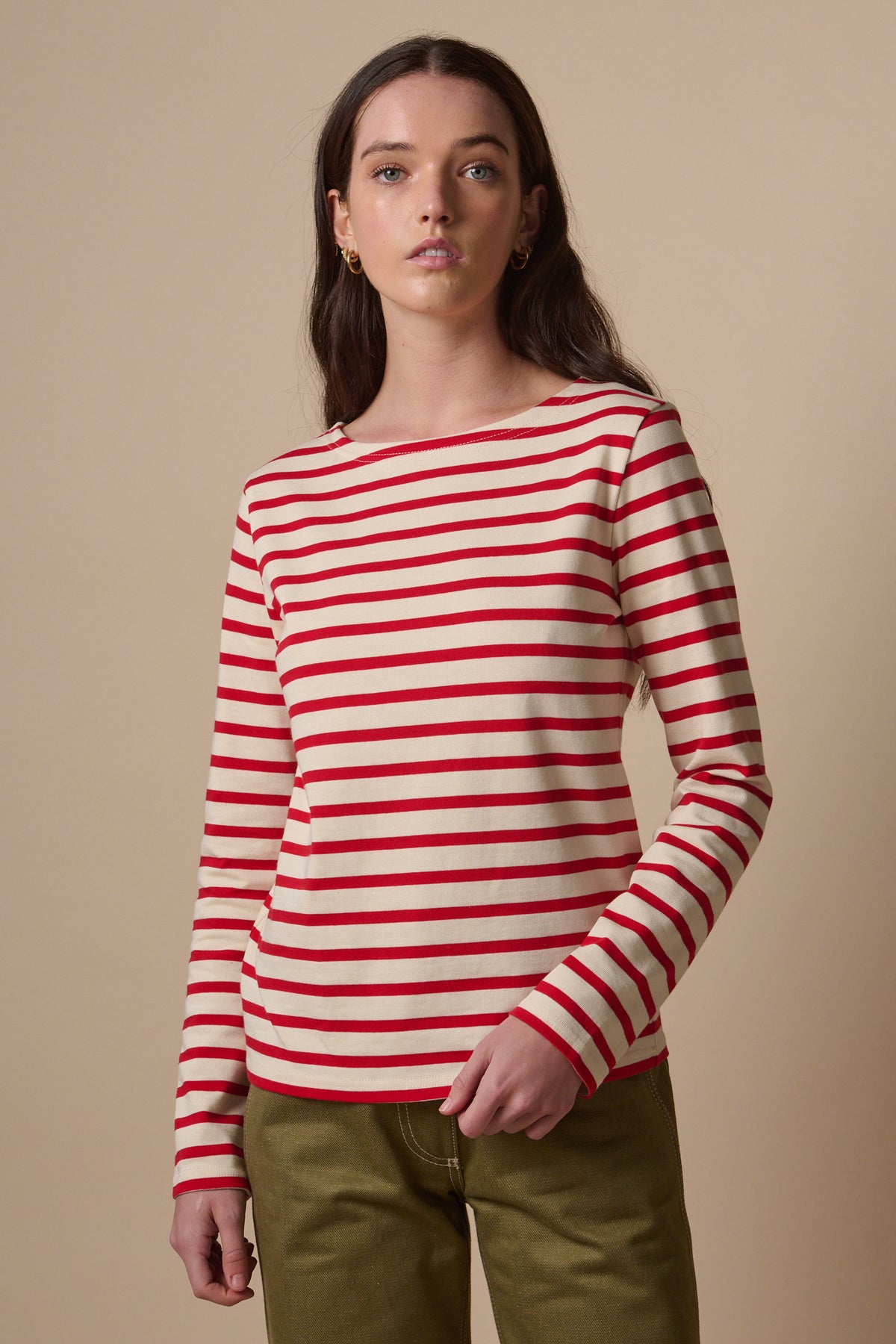 White female with long brunette hair wearing long sleeve Breton in ecru and red