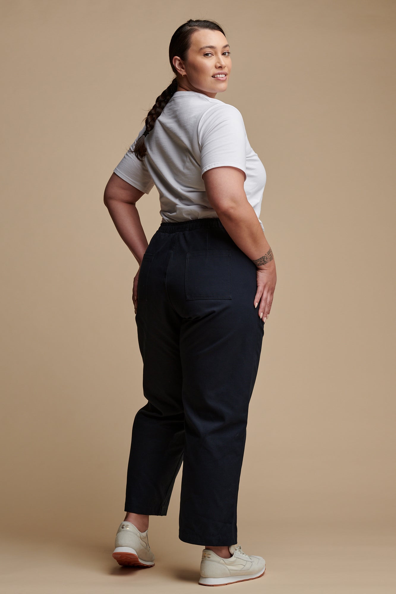 The back of female wearing camerawoman drawstring tapered cotton canvas trousers in navy paired with v neck T shirt in white.