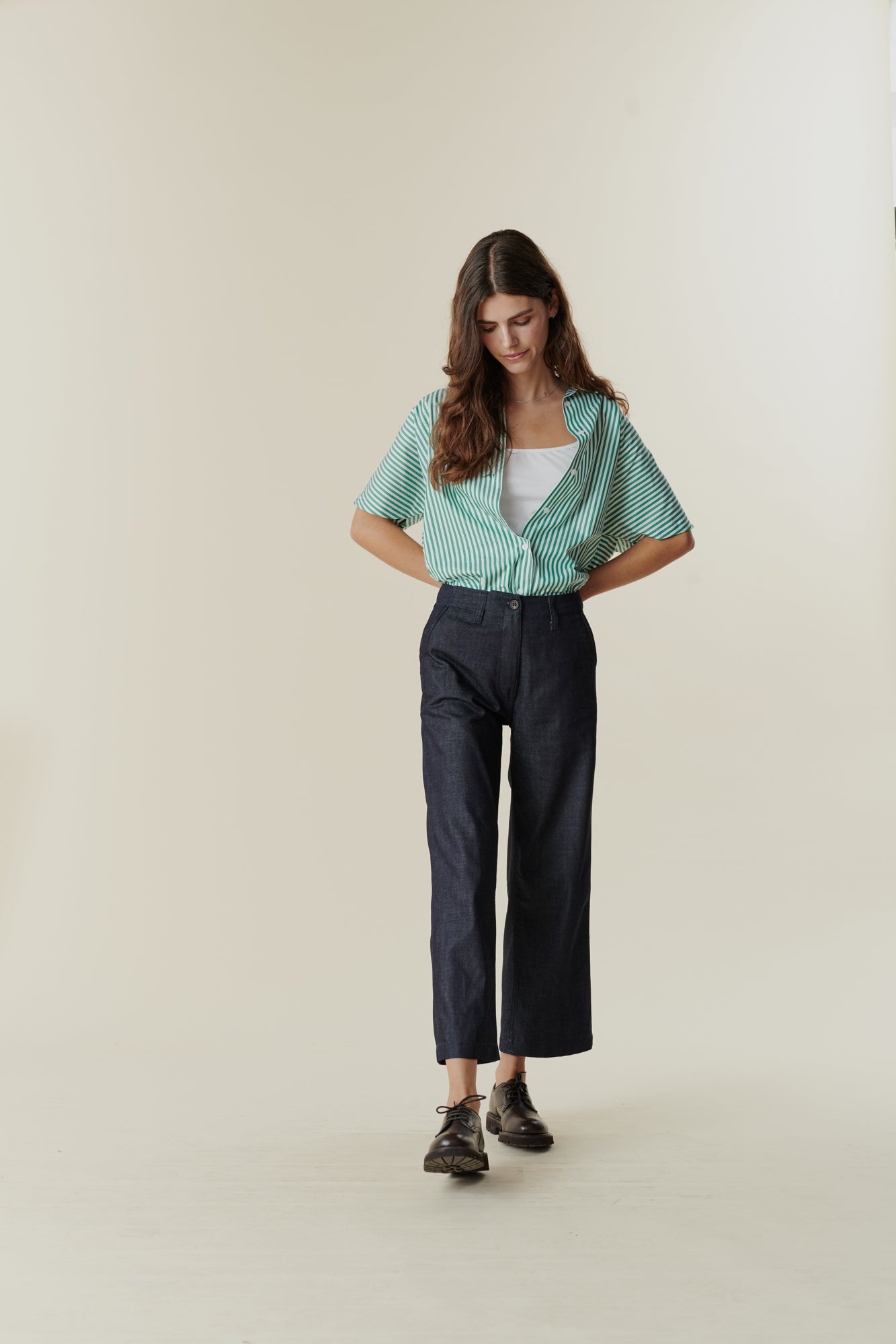 Full body front image of female wearing cropped work trousers in denim 