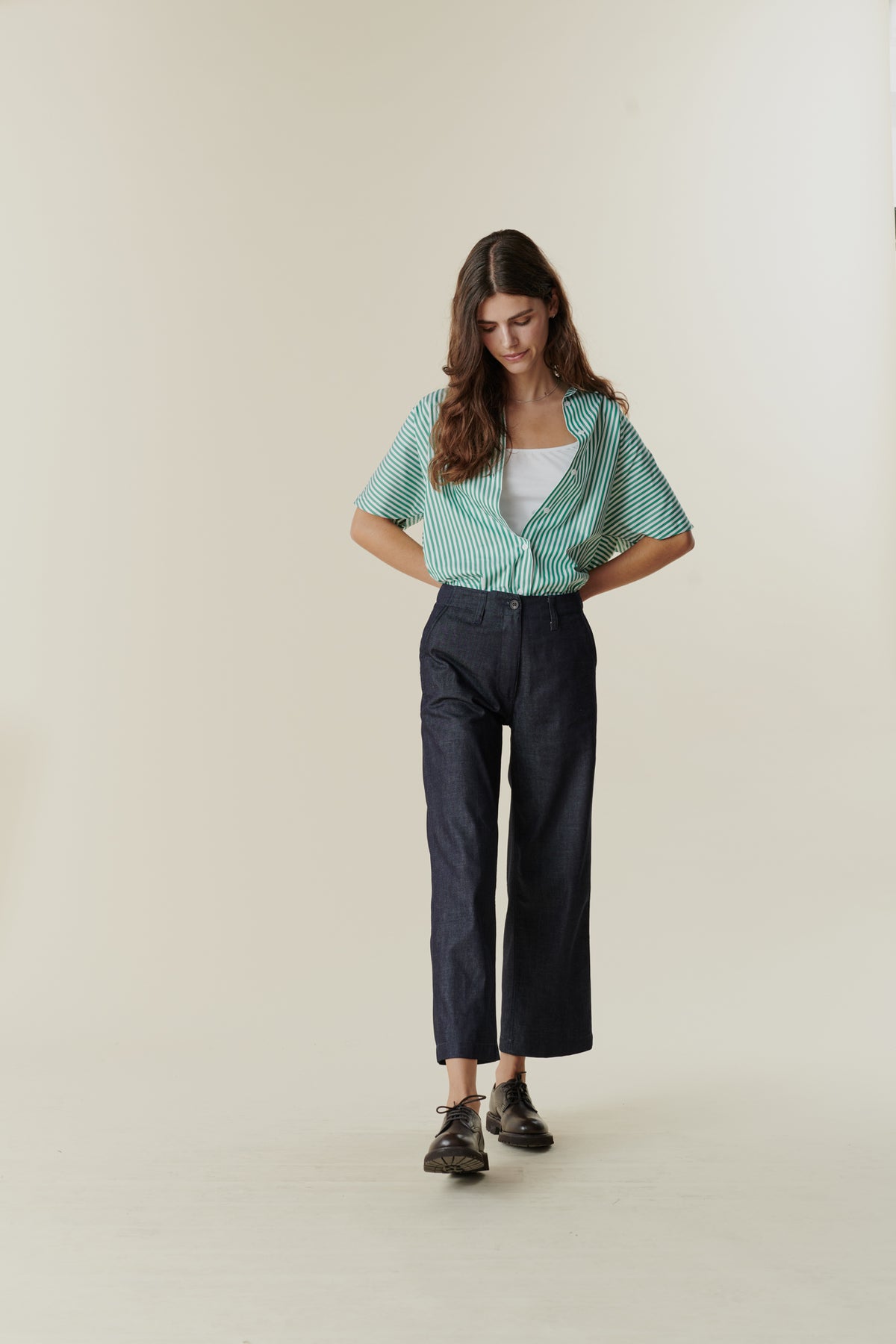 Full body front image of female wearing cropped work trousers in denim 