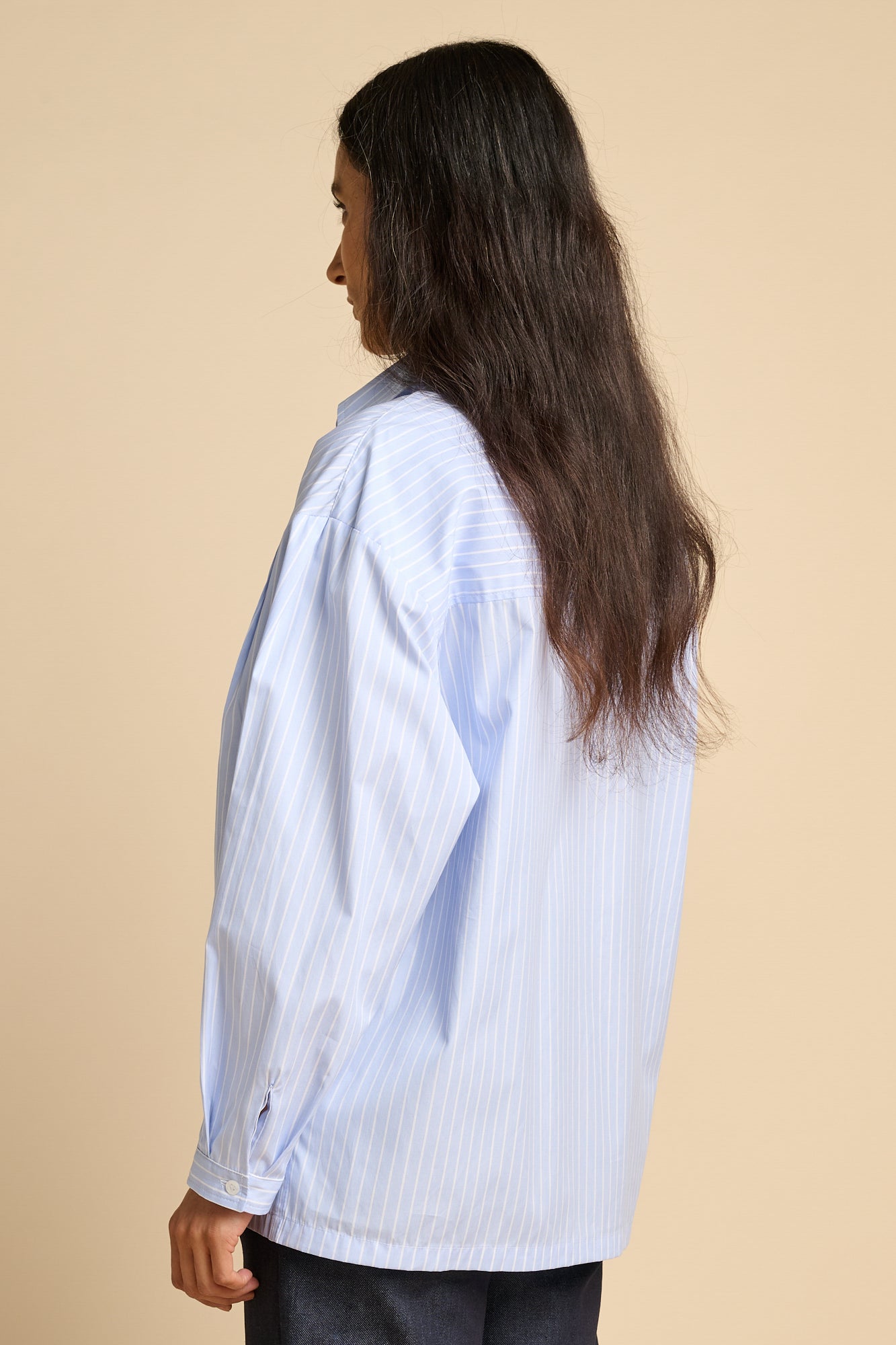 The back of woman wearing long sleeve Esme shirt in pale blue and white stripe.