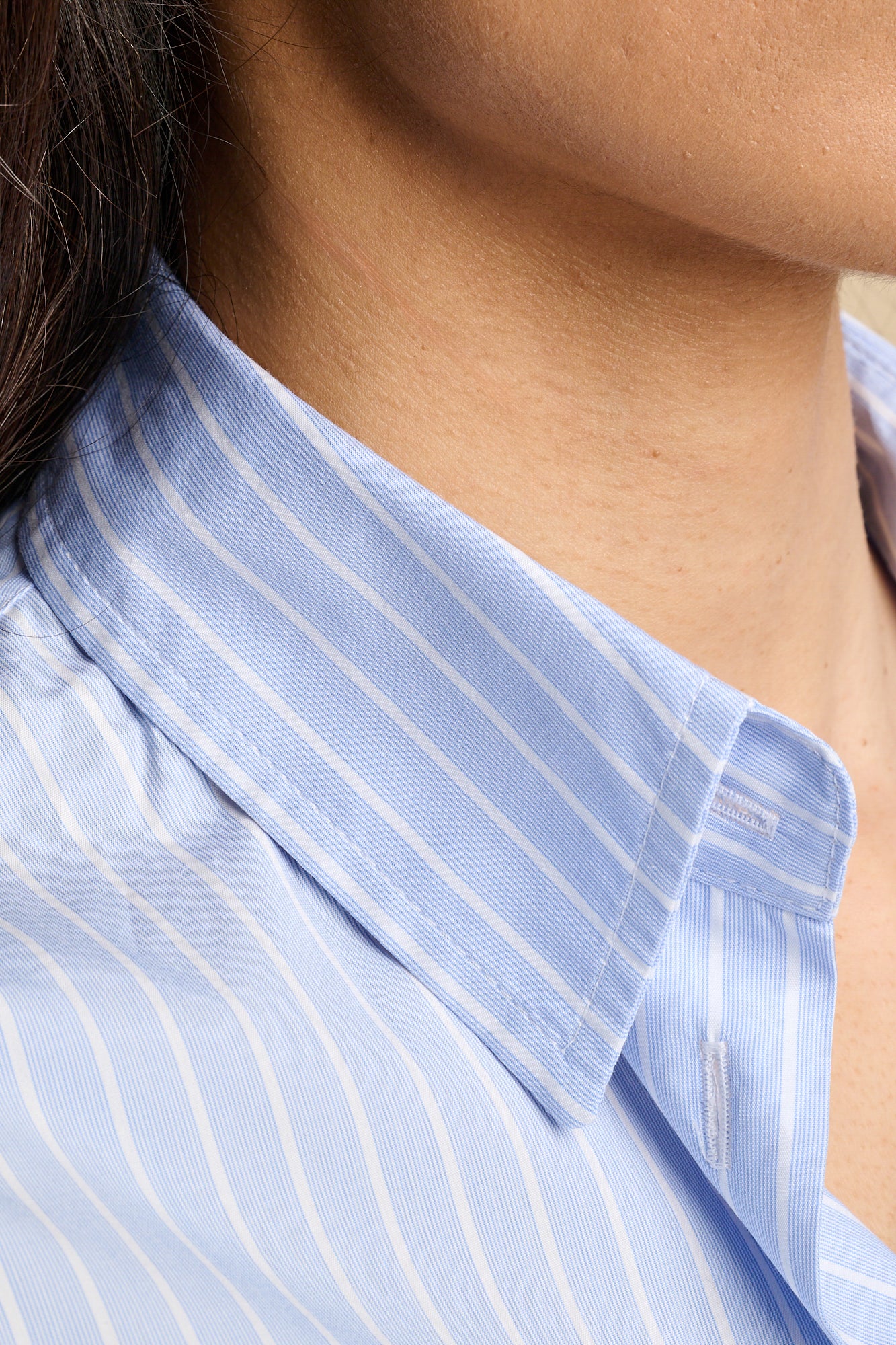 Close up of the collar of a blue and white stripe shirt.