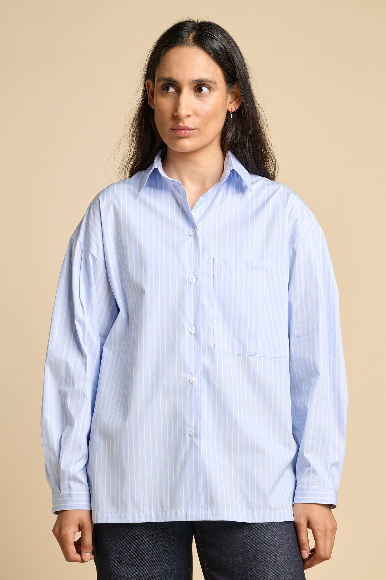 A woman wearing long sleeve shirt in pale blue and white stripe.