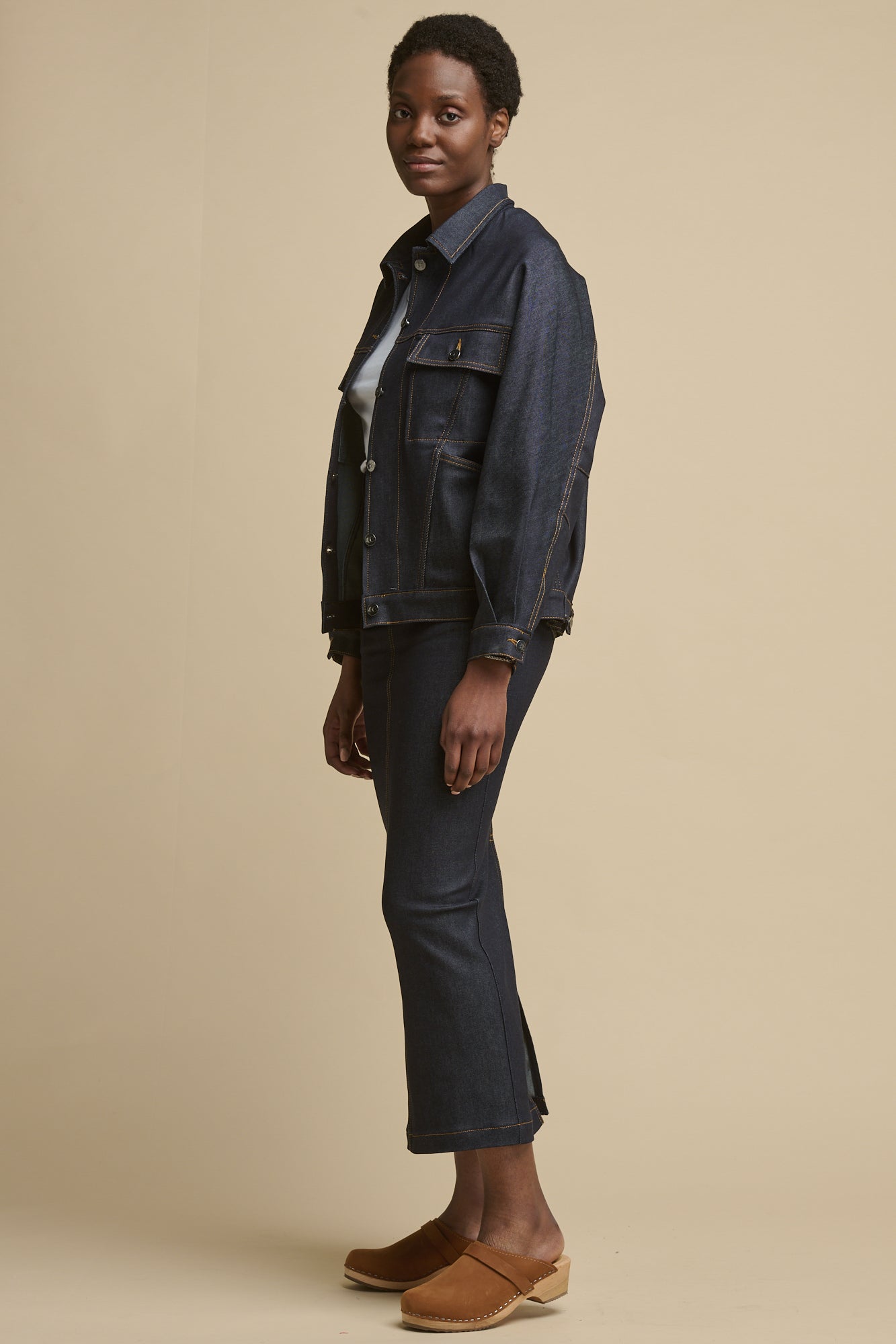 full body image of the side of female wearing Frankie denim maxi skirt with split hem paired with matching indigo denim Jodie jacket
