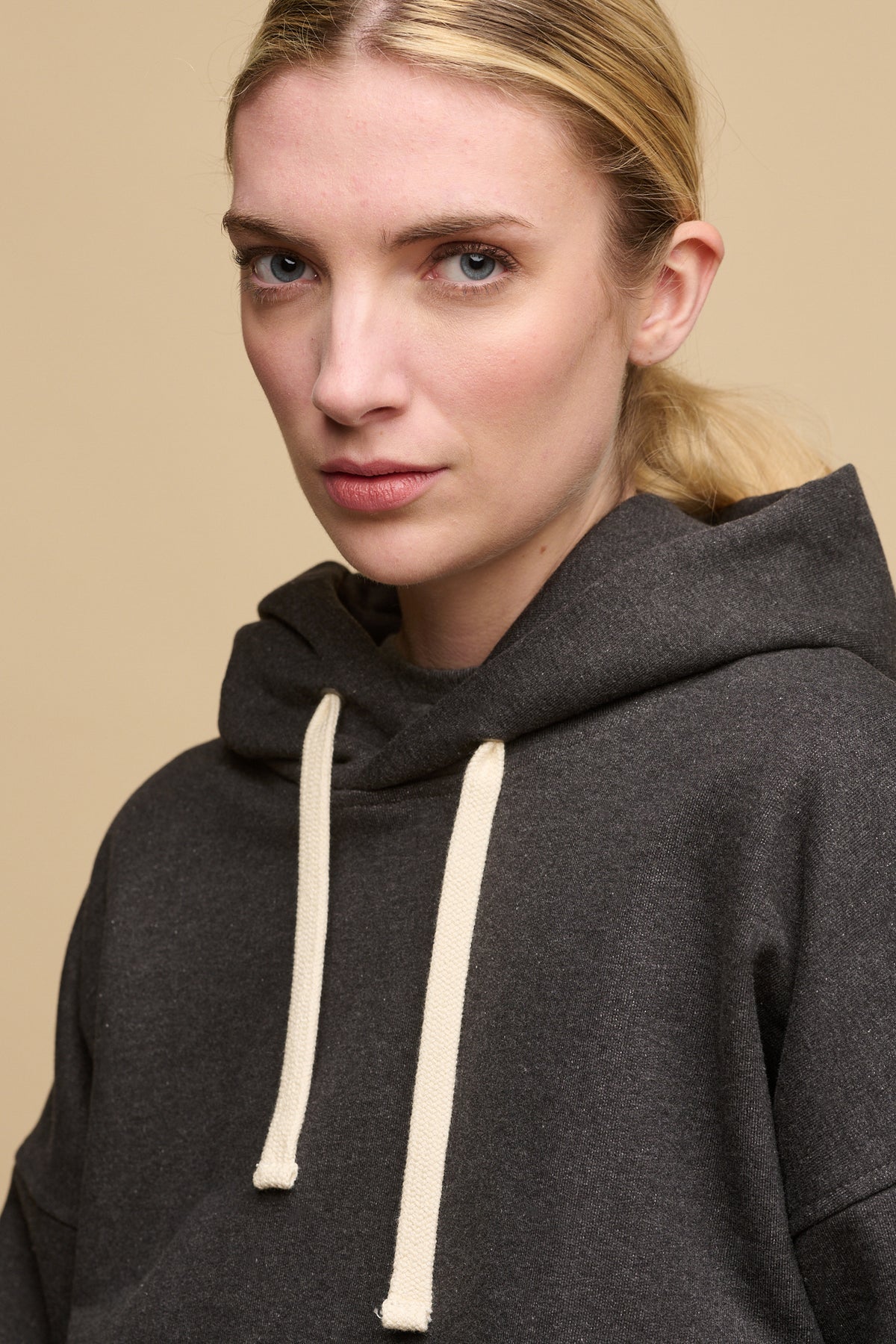 Portrait of blonde female wearing heritage hooded sweatshirt in charcoal 