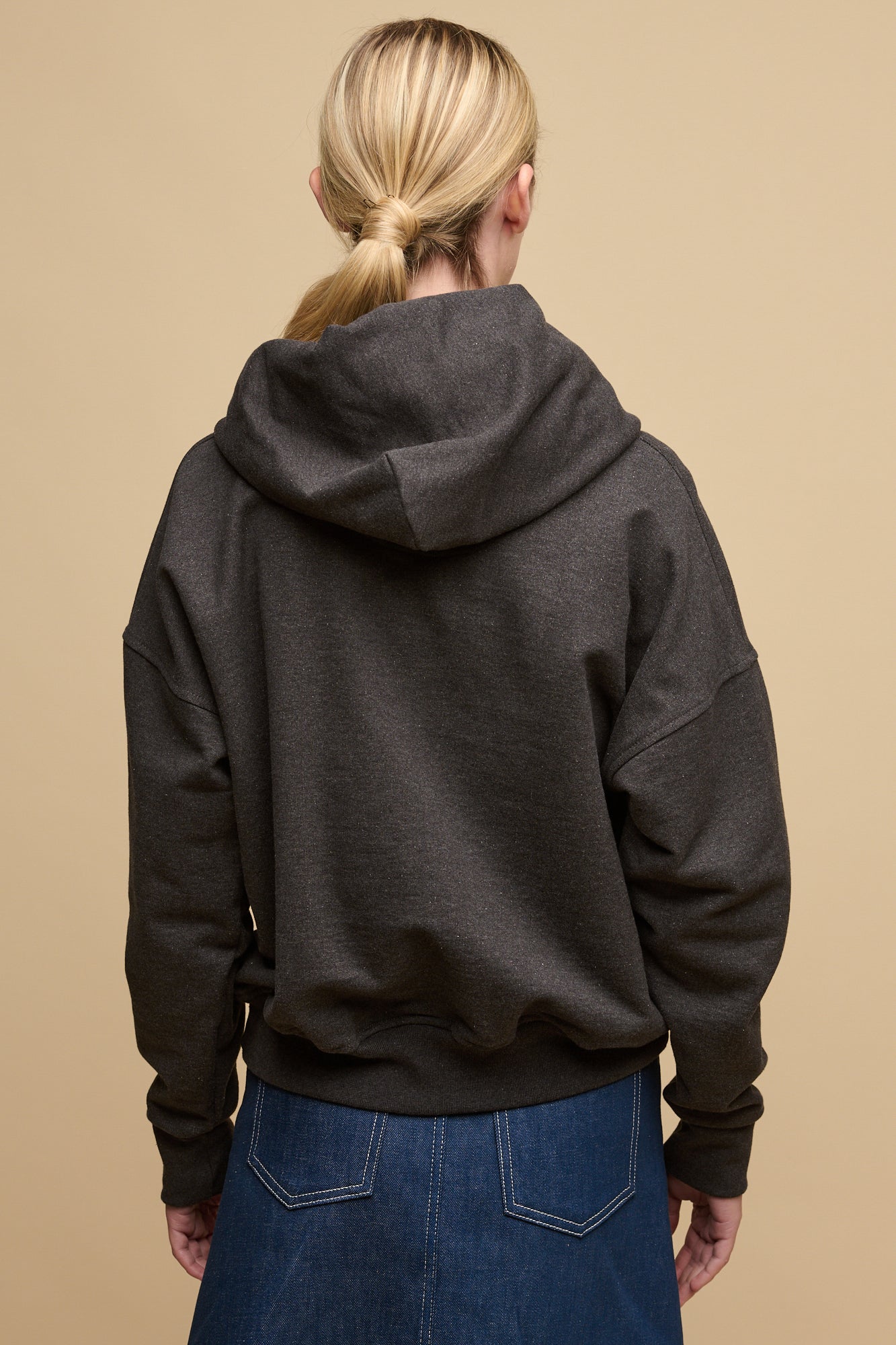 The back of blonde female wearing heritage hooded sweatshirt in charcoal
