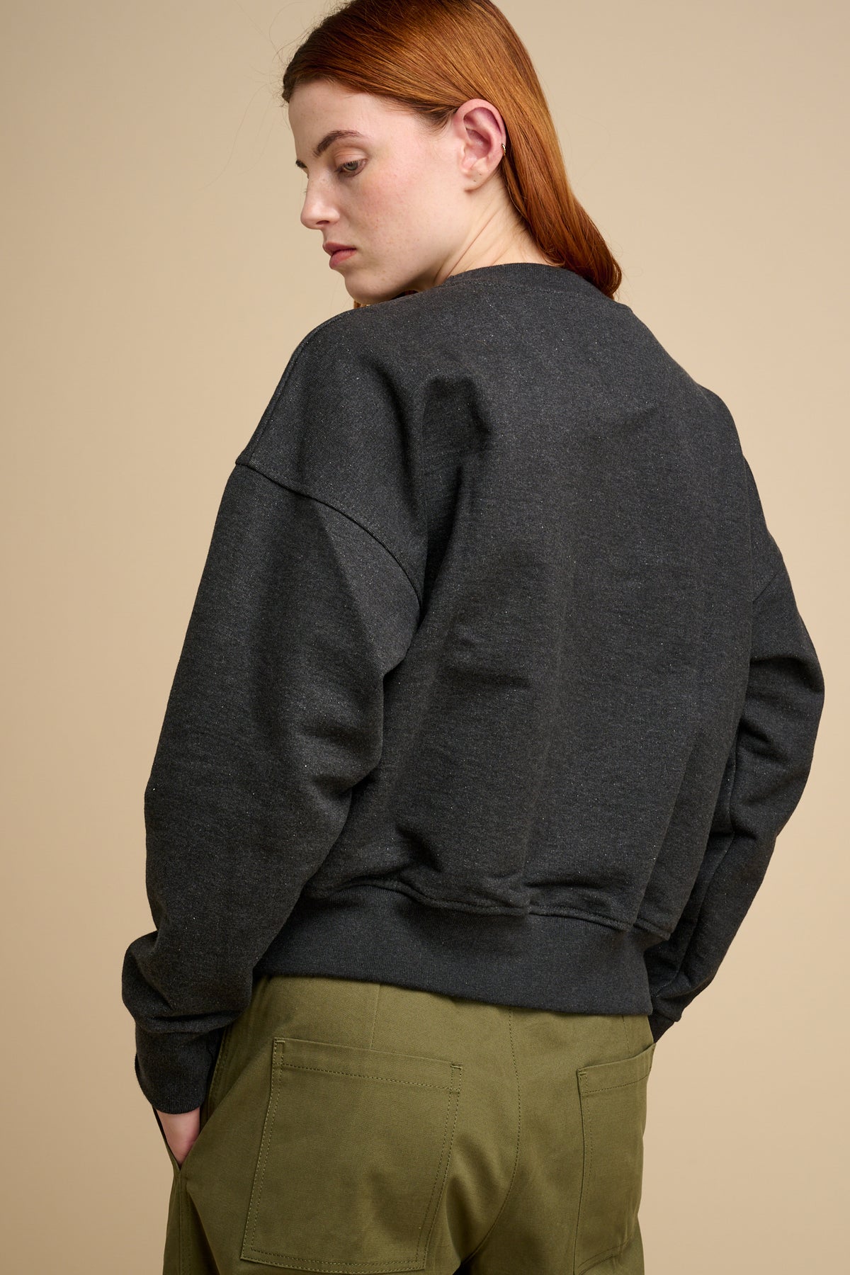 The back of woman wearing charcoal heavyweight sweatshirt  with olive trousers.
