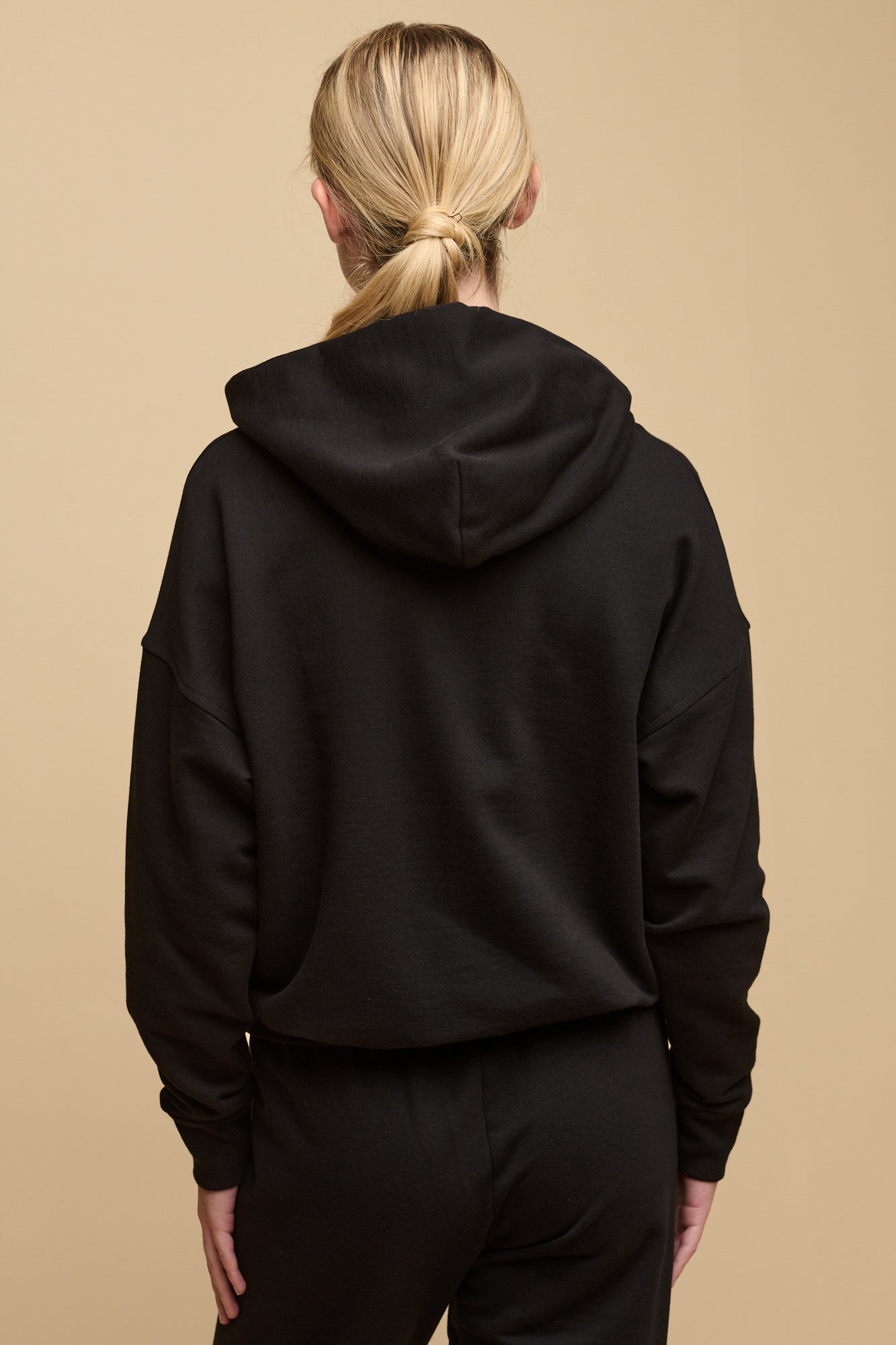 The back of female wearing hooded sweatshirt in black
