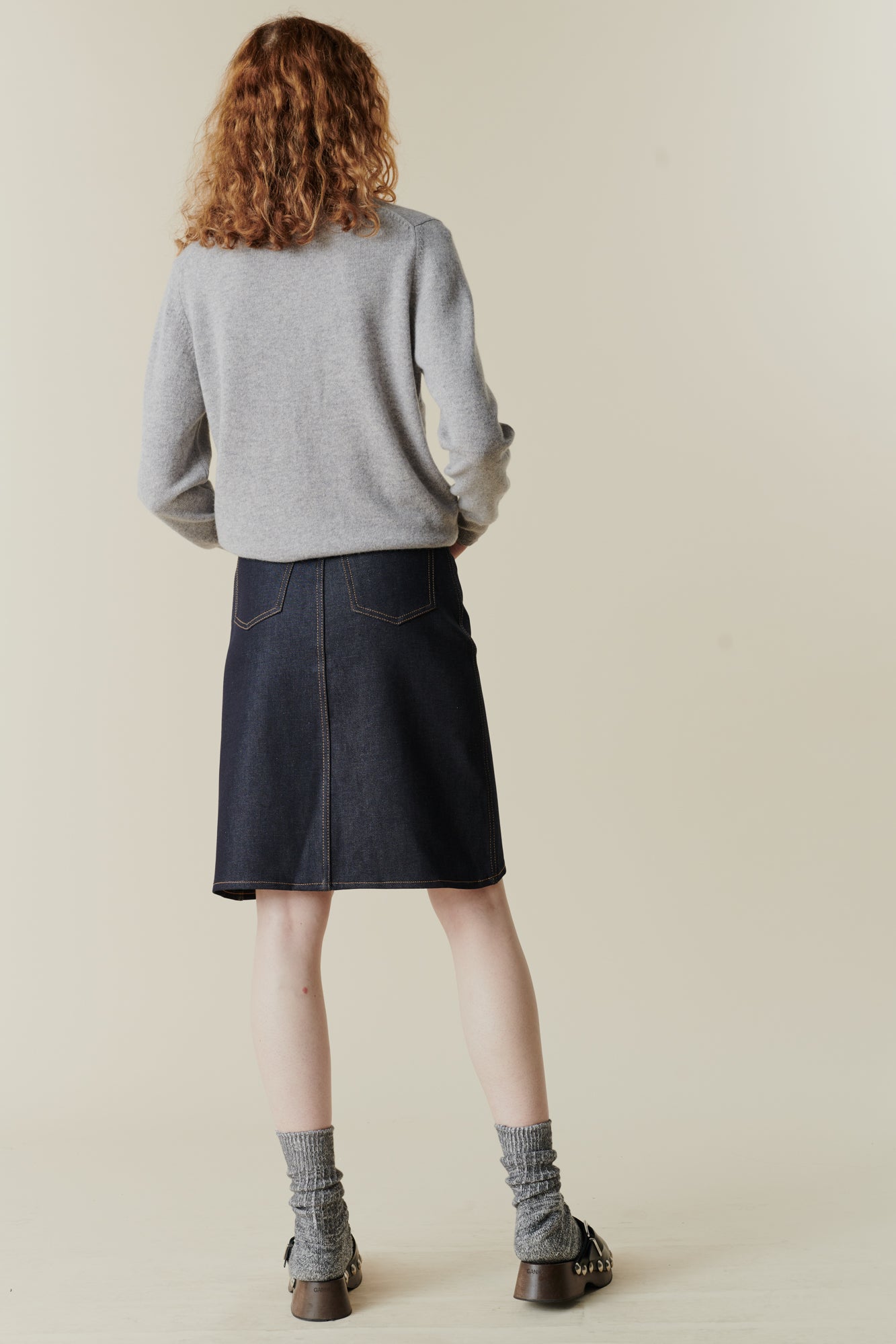 Female wearing knee length jean skirt in indigo with back pockets
