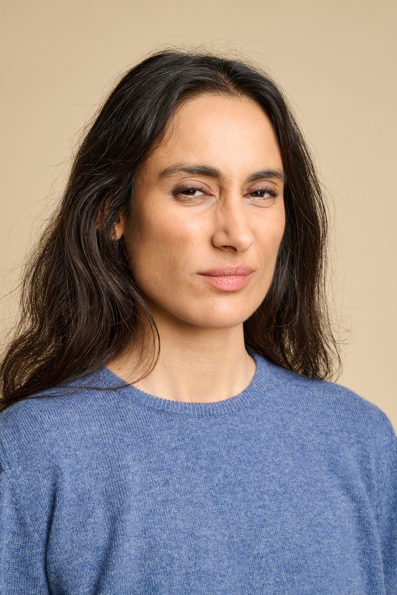 Portrait of a woman wearing lambswool crew neck jumper in denim marl paired with blue jeans.