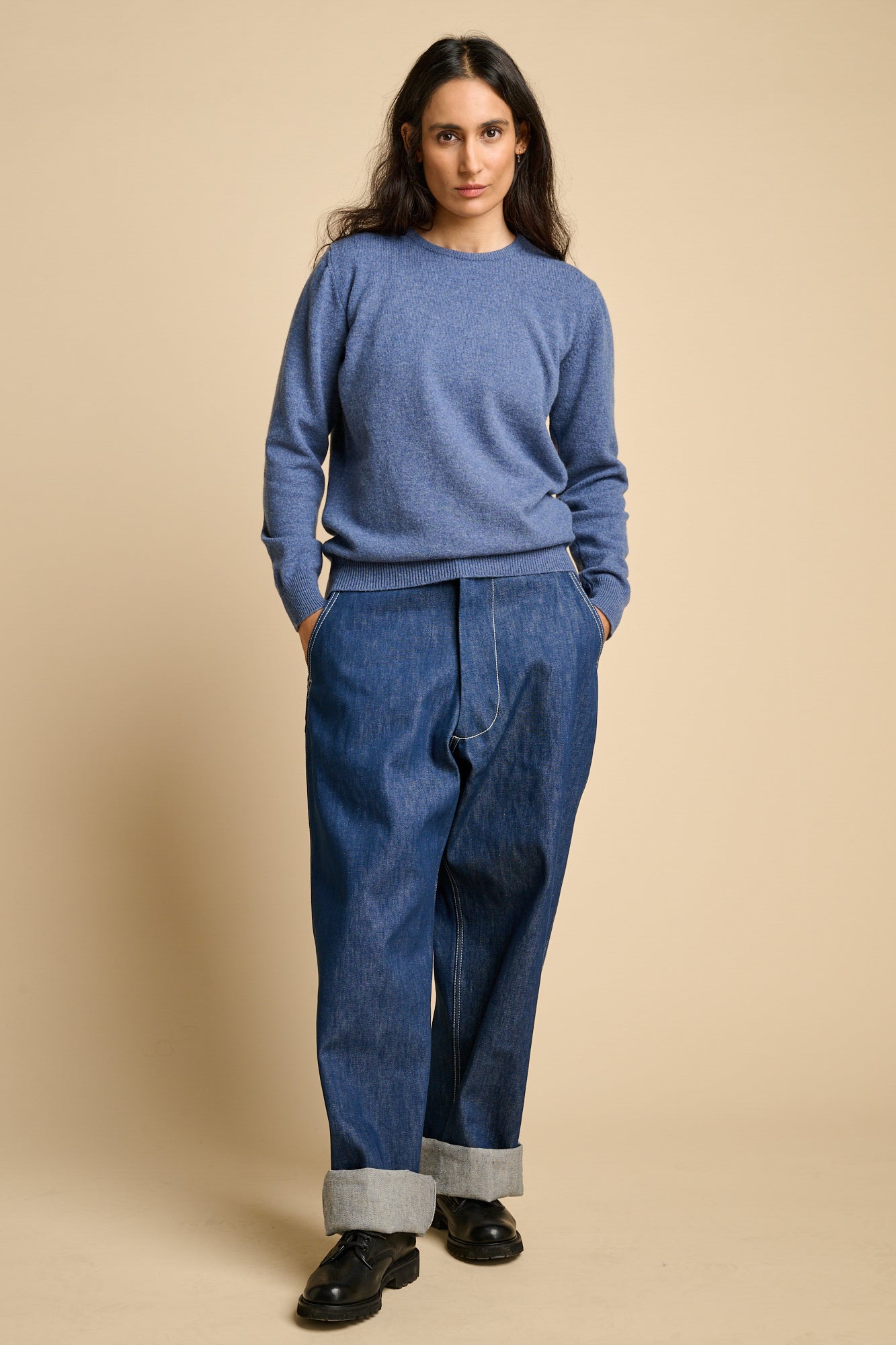 A woman wearing lambswool crew neck jumper in denim marl paired with blue wide leg jeans.