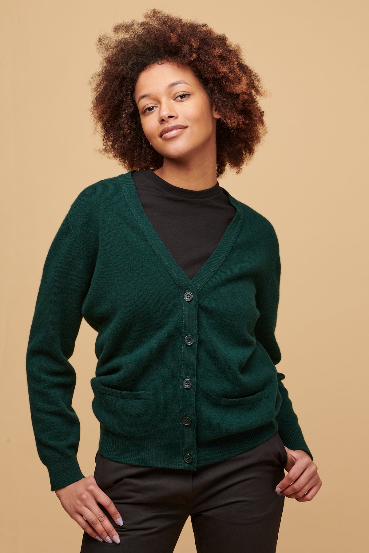 Black female, smiling wearing buttoned Lambswool v neck cardigan over black t shirt 
