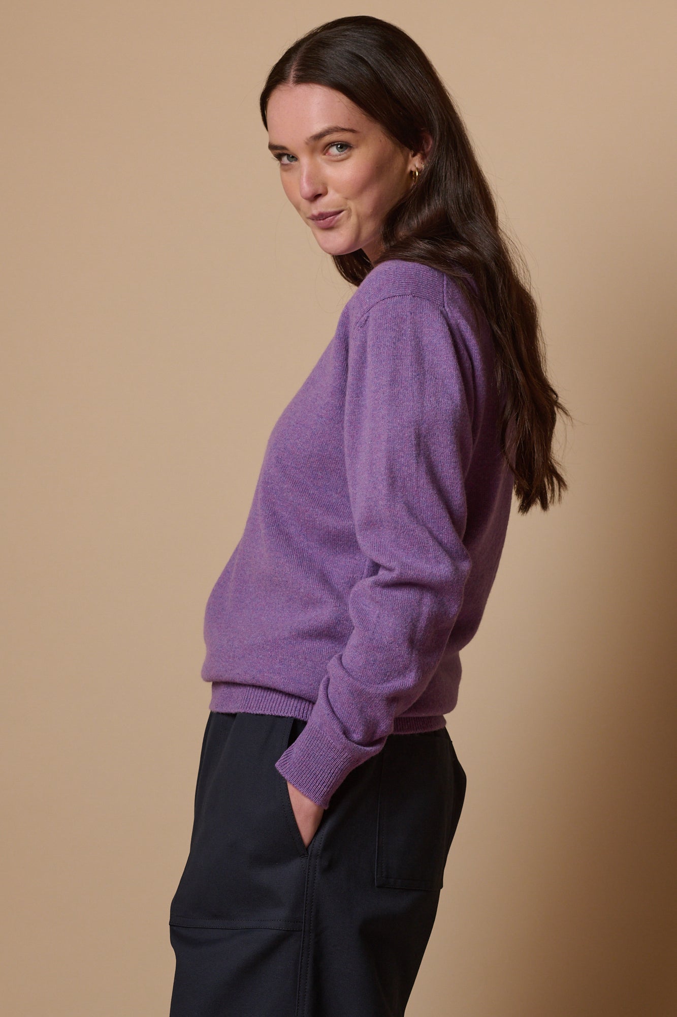 brunette model with long hair image from the side wearing lambswool crew neck in thislt purple