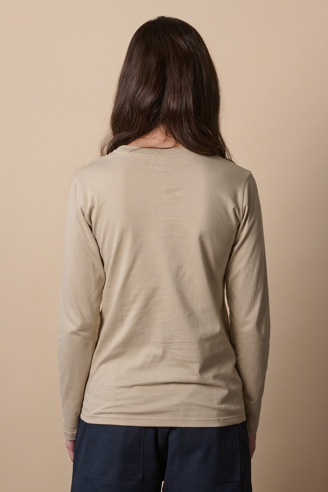 Thigh up image of the back of female wearing long sleeve t shirt in stone