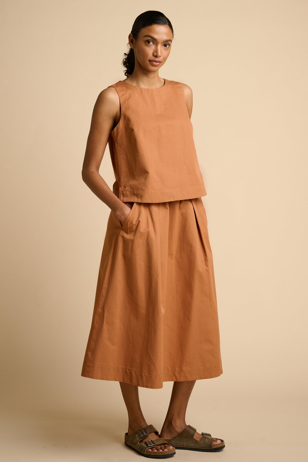 Woman wearing cinnamon top and skirt.