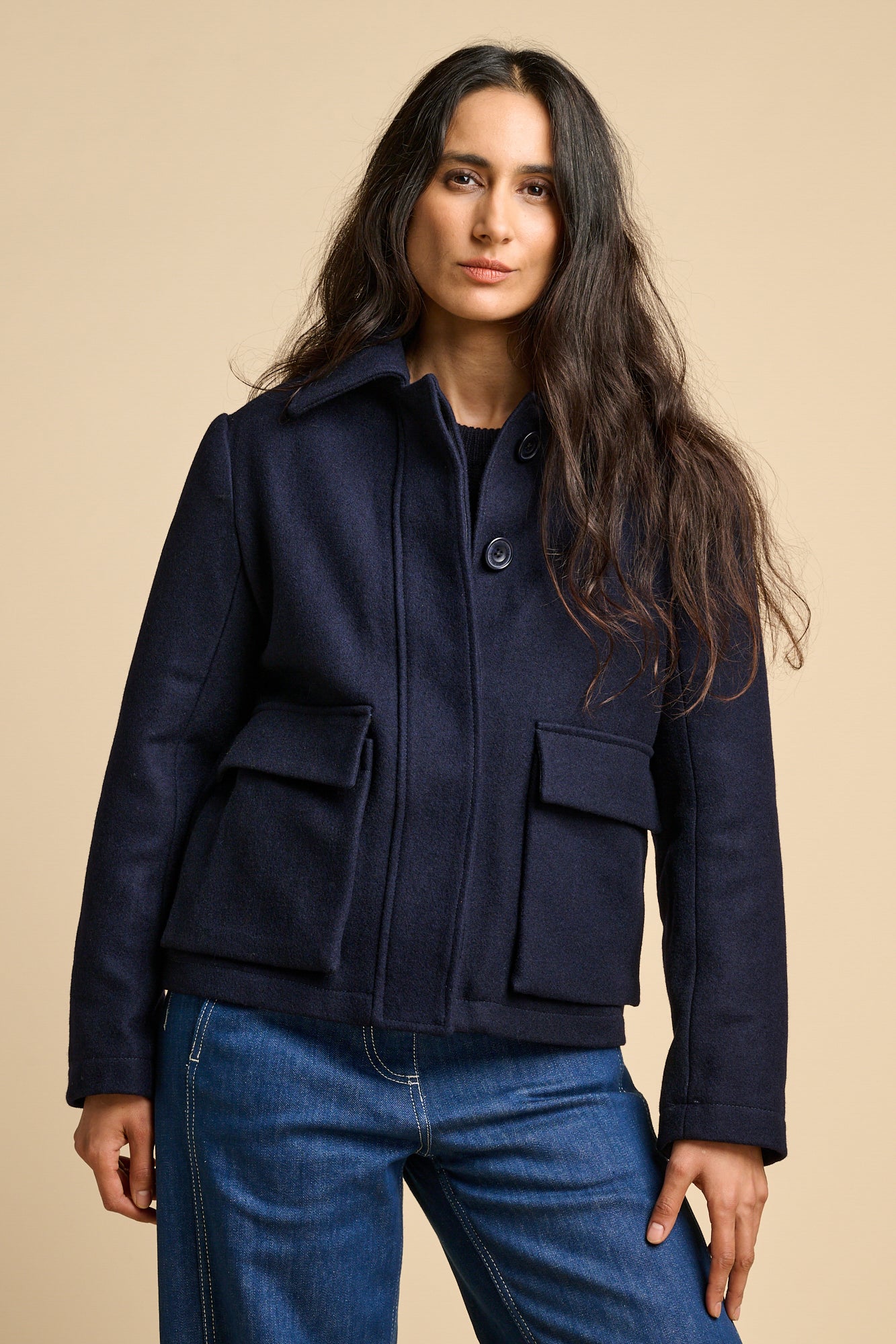 A woman wearing Nancy short wool coat in navy paired with blue jeans.