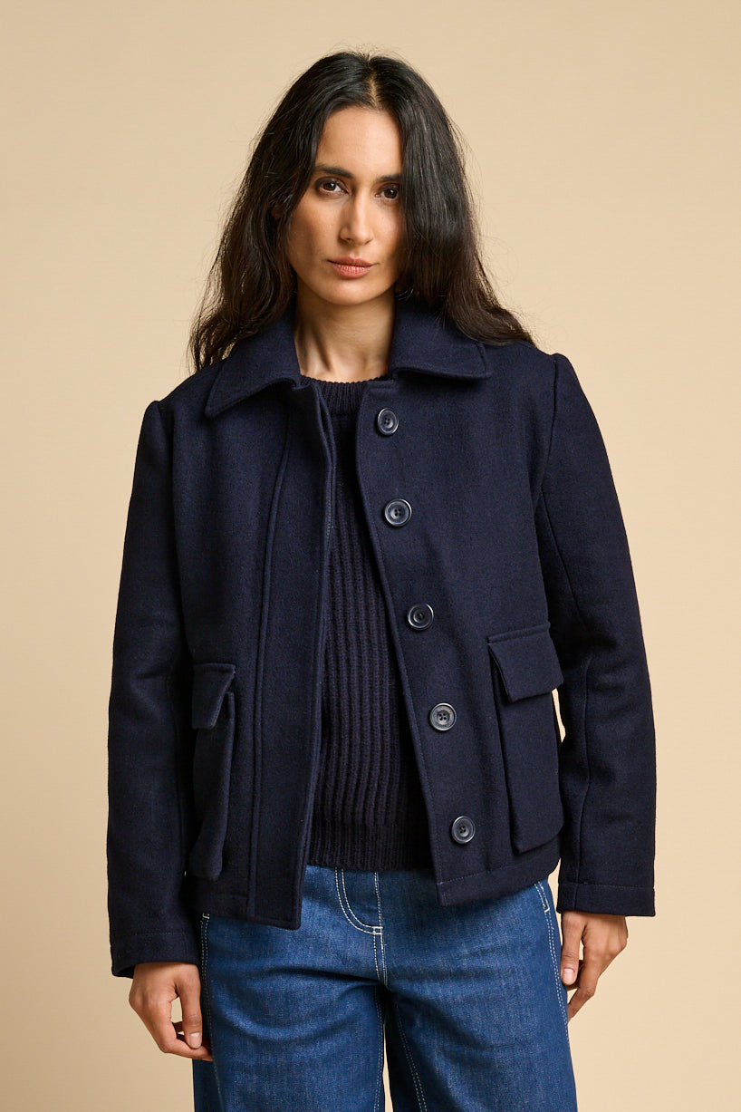 A woman wearing Nancy short wool coat in navy with button up front.