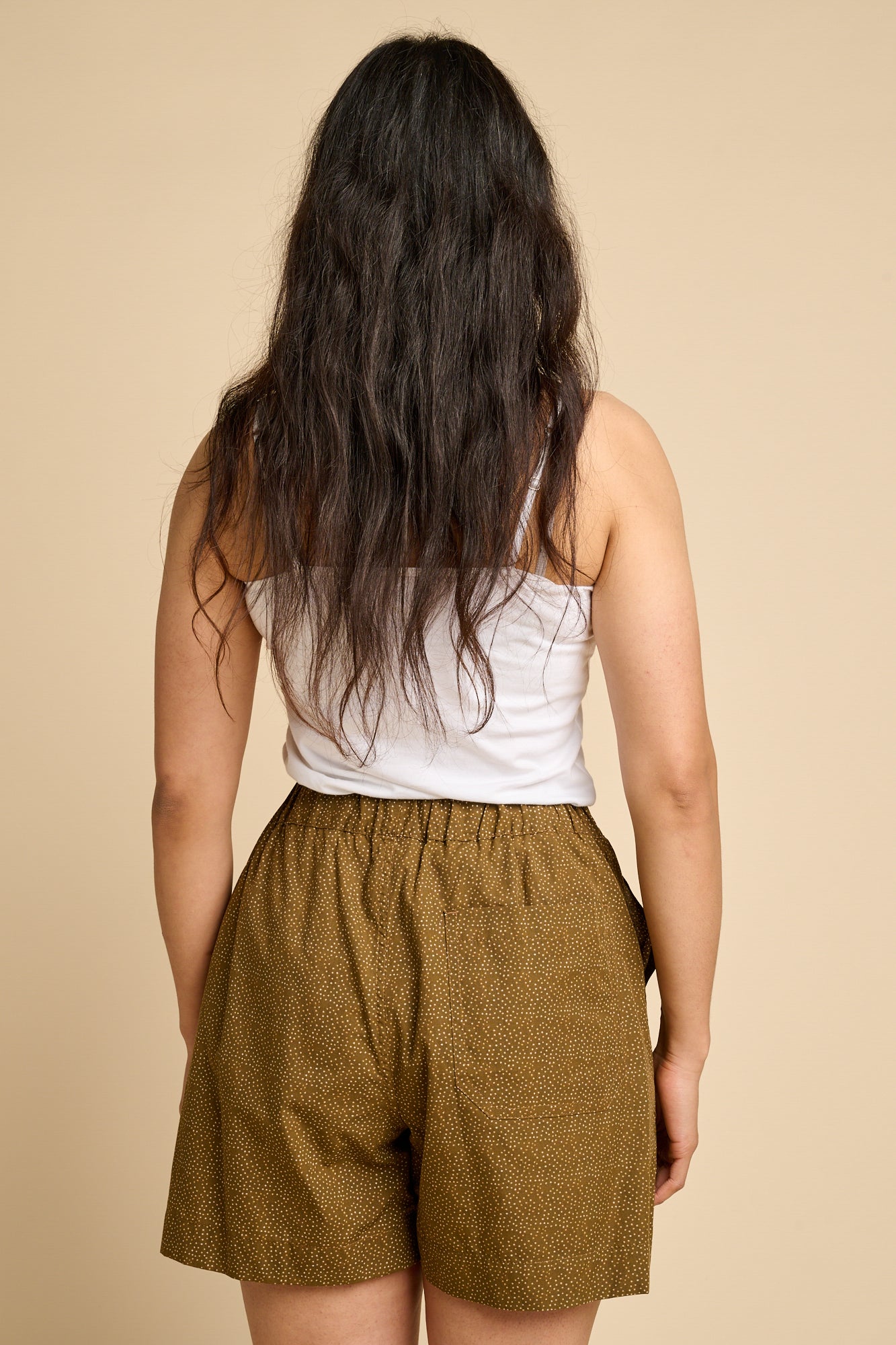 The back of a woman wearing white cami and brown polka dot pull up shorts. 
