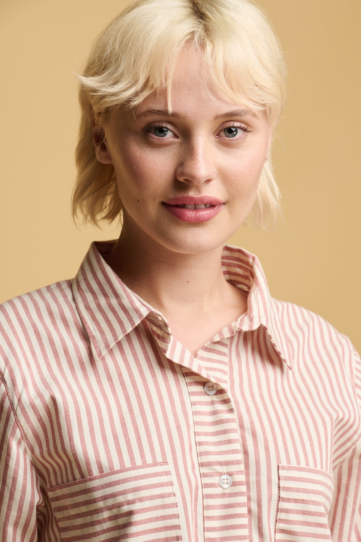 Portrait of blonde female wearing Olivia half placket shirt dress in red and white stripes with two chest pockets