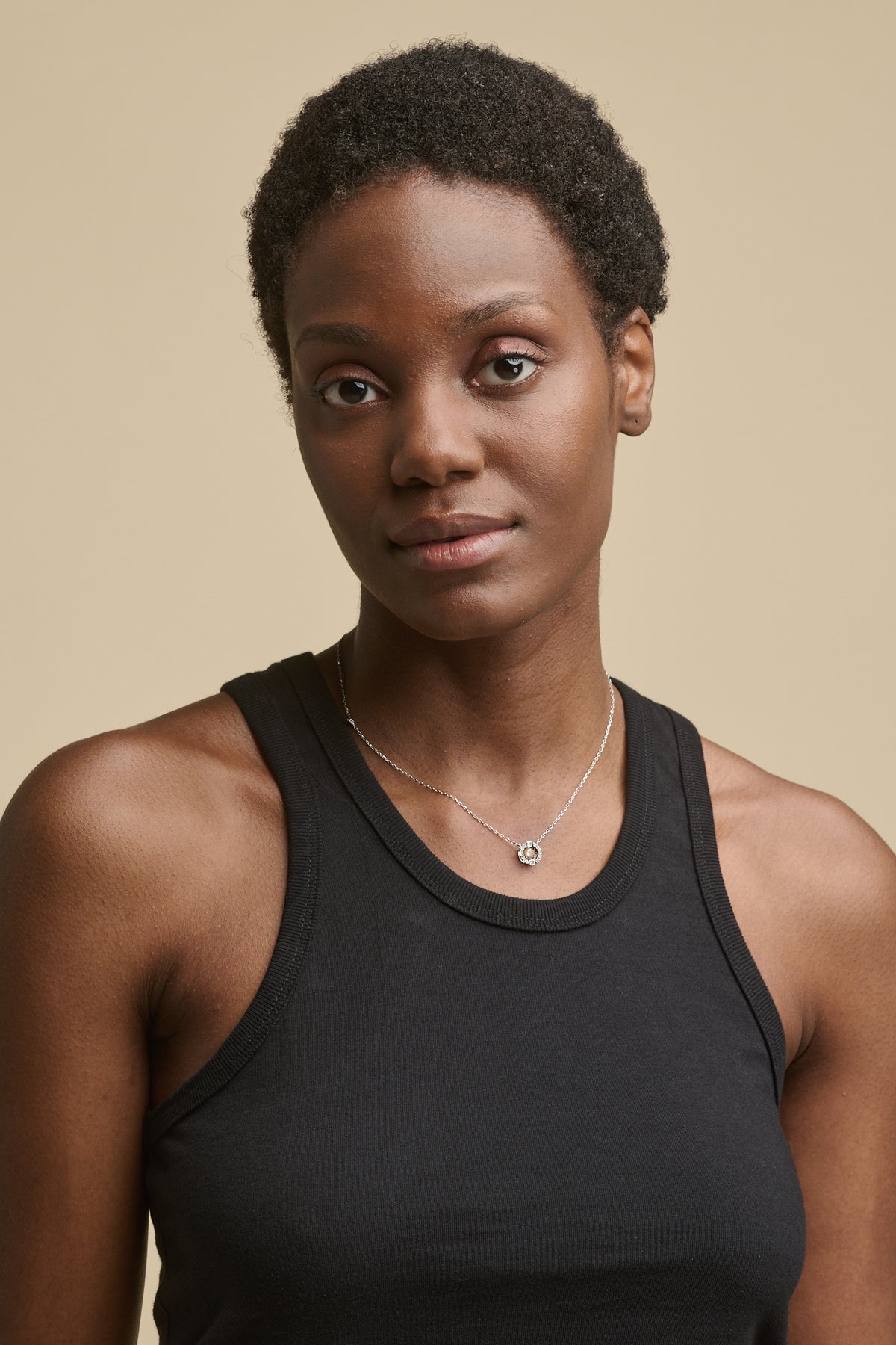 Portrait of black female with short hair and brown eyes wearing racer back vest in black 