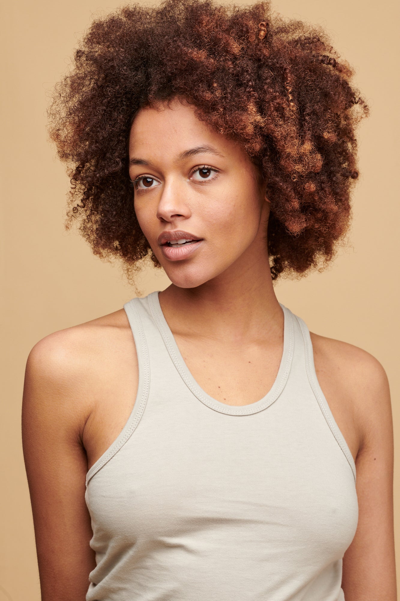 Portrait of female of colour with afro wearing racer back vest in stone