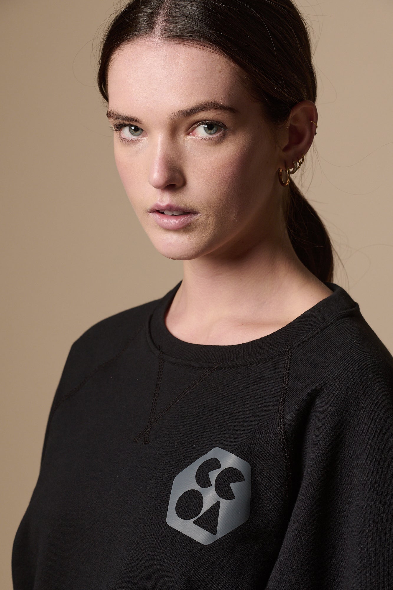 Portrait of female wearing raglan sweatshirt in black with CCOA logo
