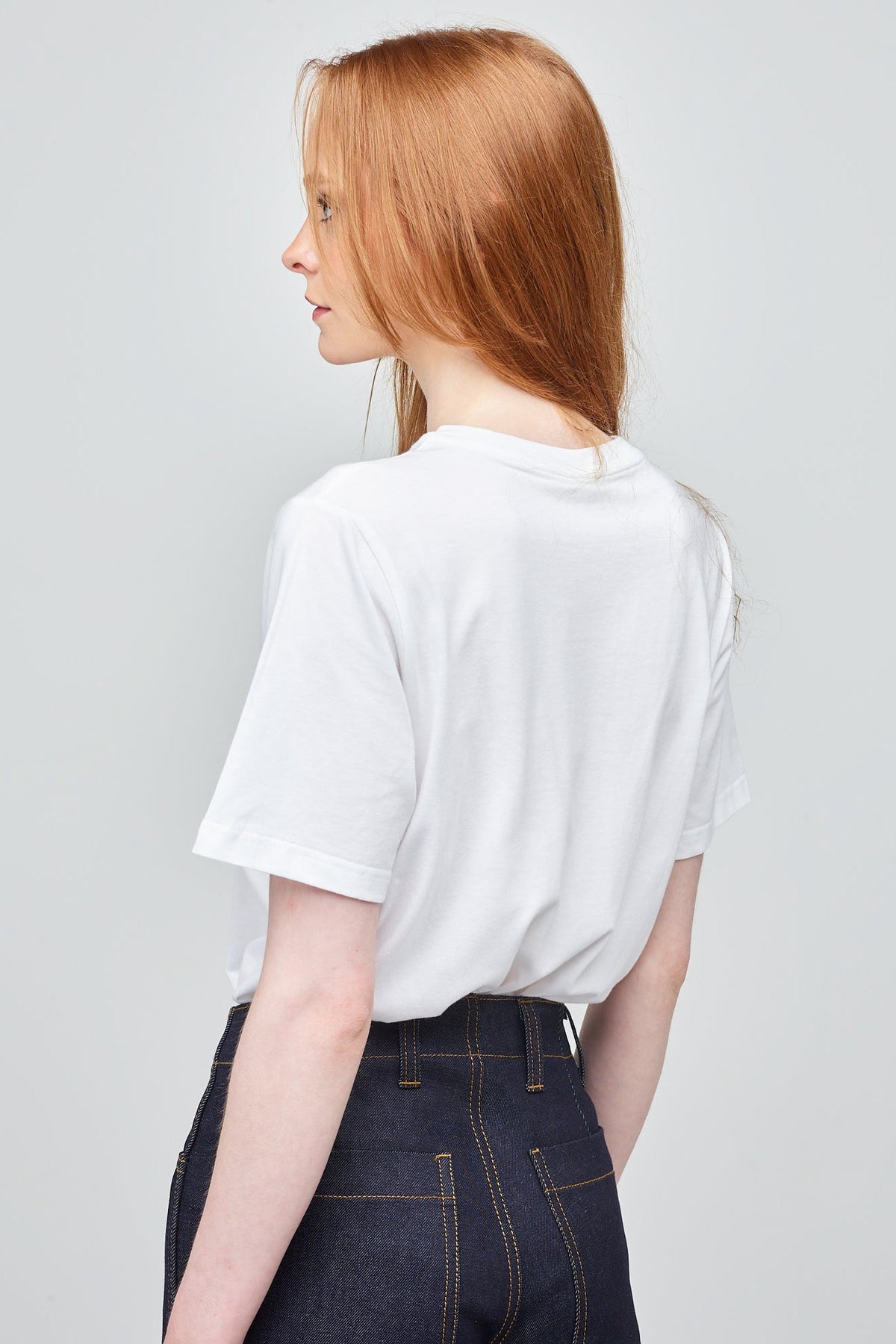 A young, white model with long ginger hair wearing a short sleeve white t-shirt
