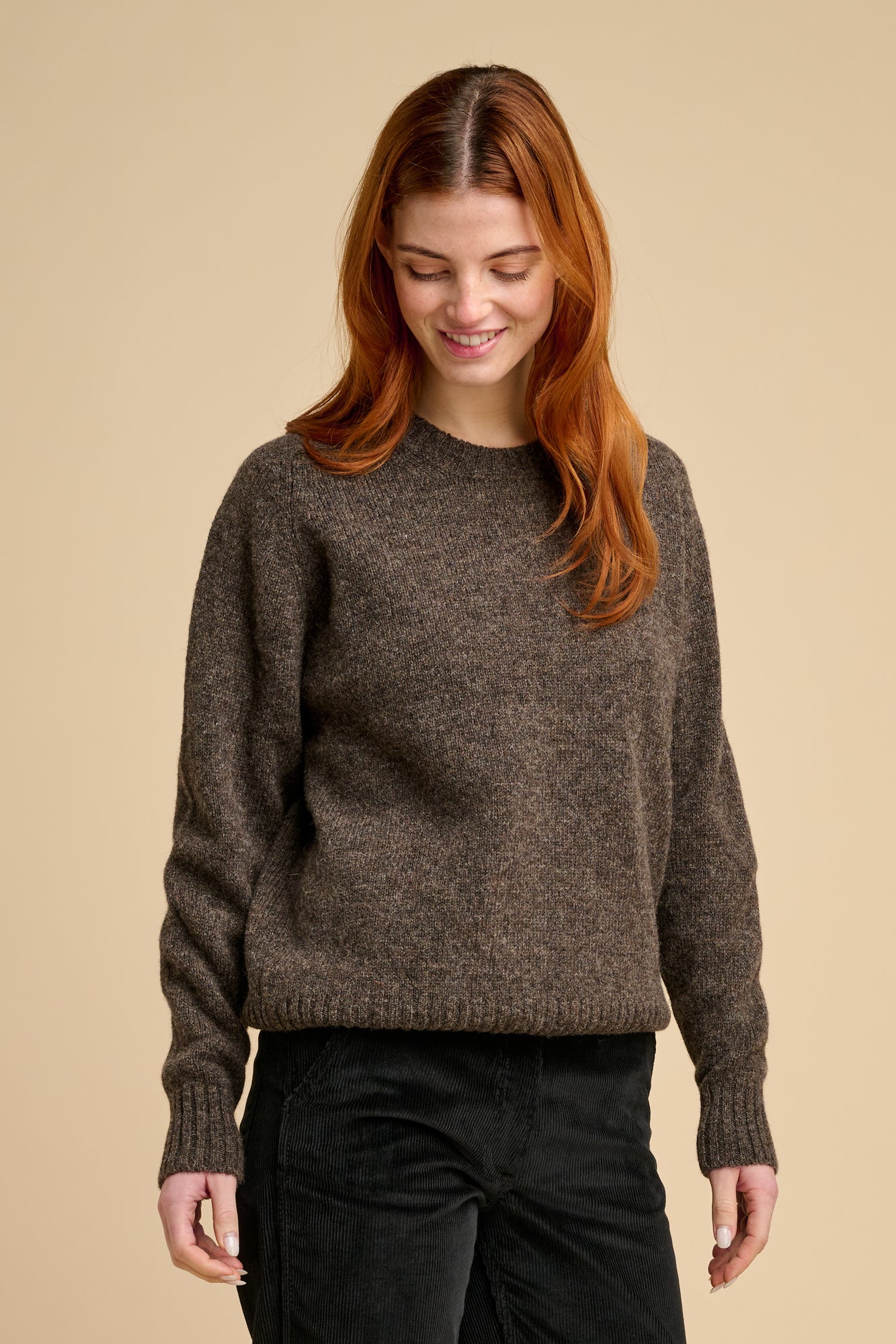 Woman wearing brown knit jumper against beige background