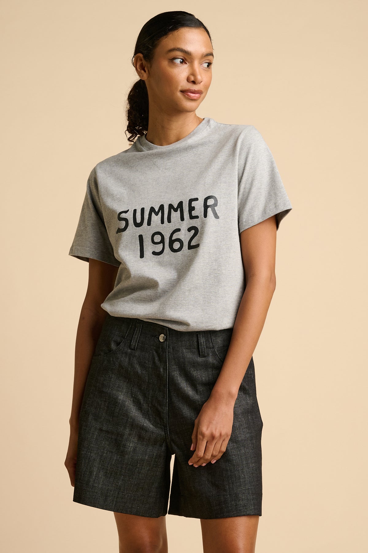 Woman wearing a grey t-shirt with 'SUMMER 1962' text graphic print.