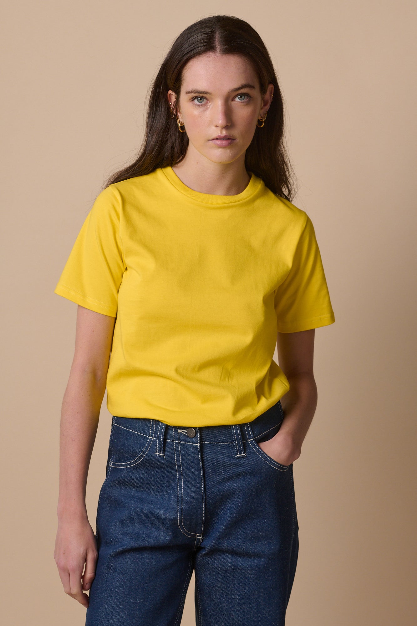 Portrait of smiley female with long brunette hair wearing short sleeve crew neck t shirt in canary yellow